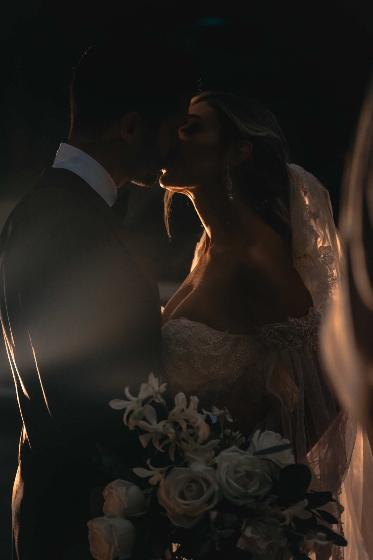 Romantic silhouette of a wedding couple with dramatic lighting and floral elements.