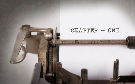 Vintage typewriter typing 'CHAPTER - ONE' on white paper with dramatic lighting and vignette effect.