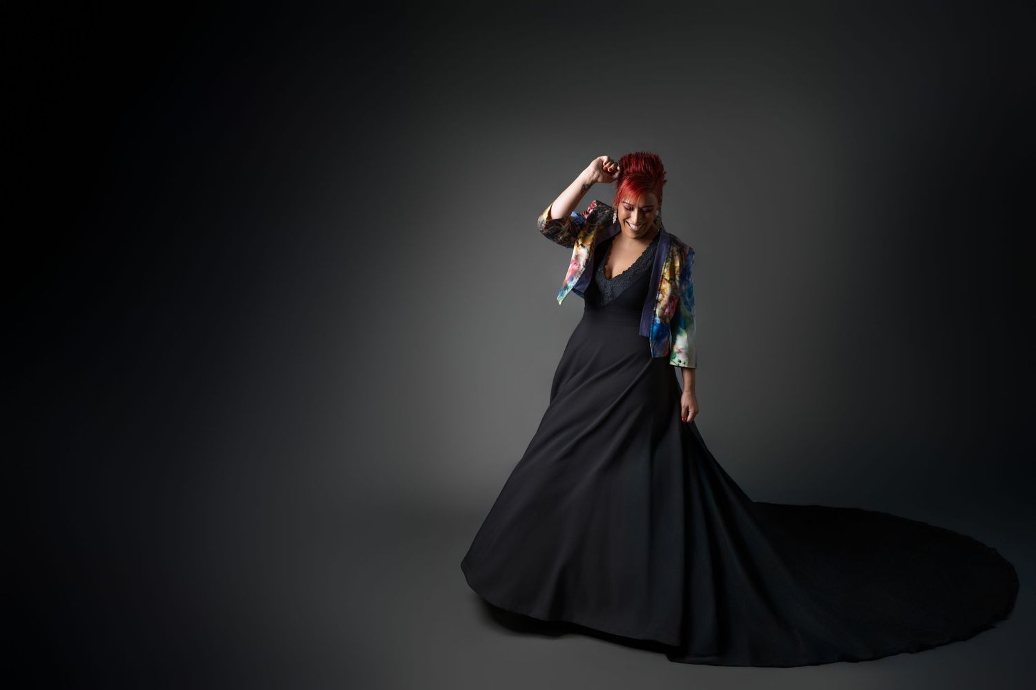 A dancer in a flowing black dress performs a dramatic spinning movement against a dark background.