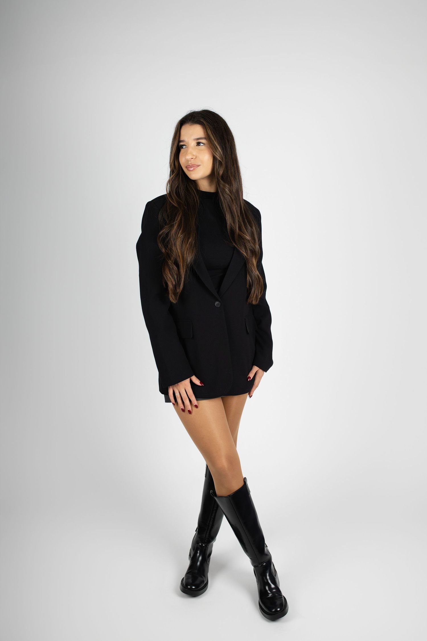 A fashion model in a black sweater dress and combat boots poses against a white backdrop in four different poses.