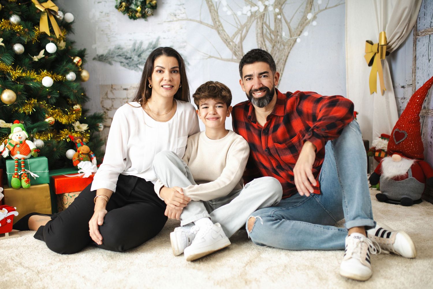People sitting on floor wearing casual winter outfits near decorated Christmas trees and holiday decor.