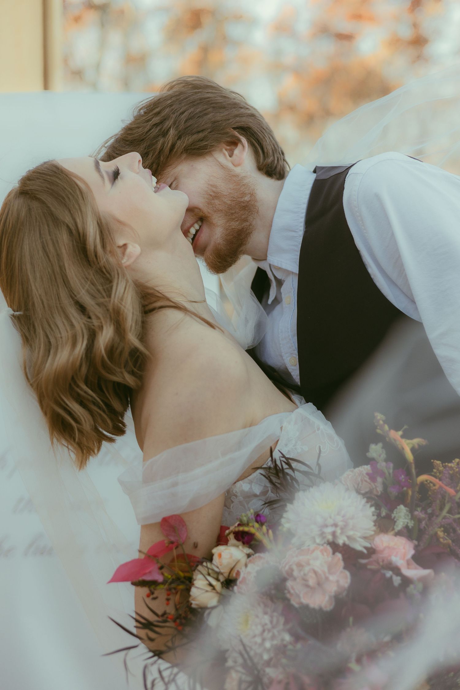 A romantic wedding photo with colorful flowers and soft autumn lighting.