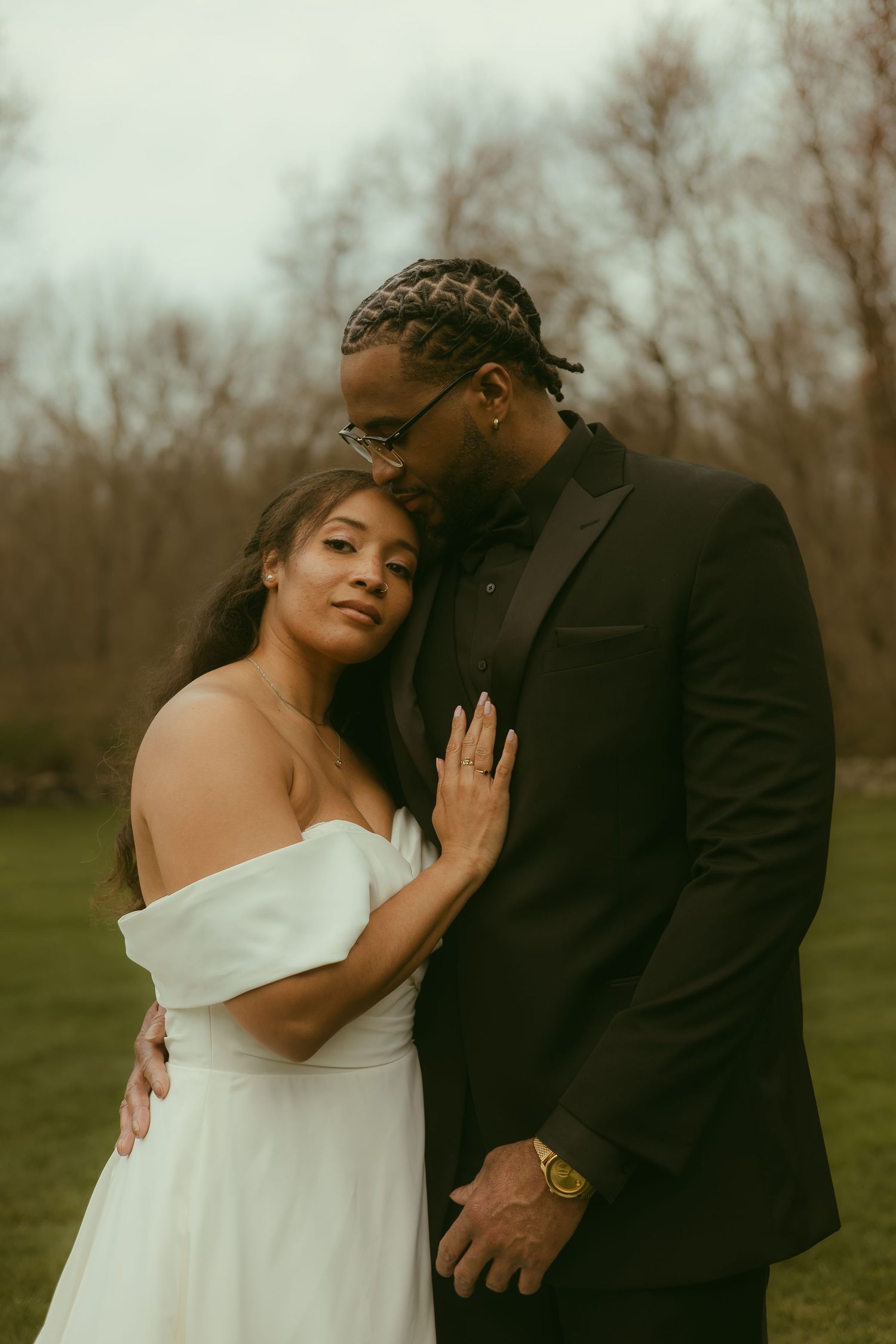 A romantic wedding portrait of a couple embracing outdoors on an overcast day.