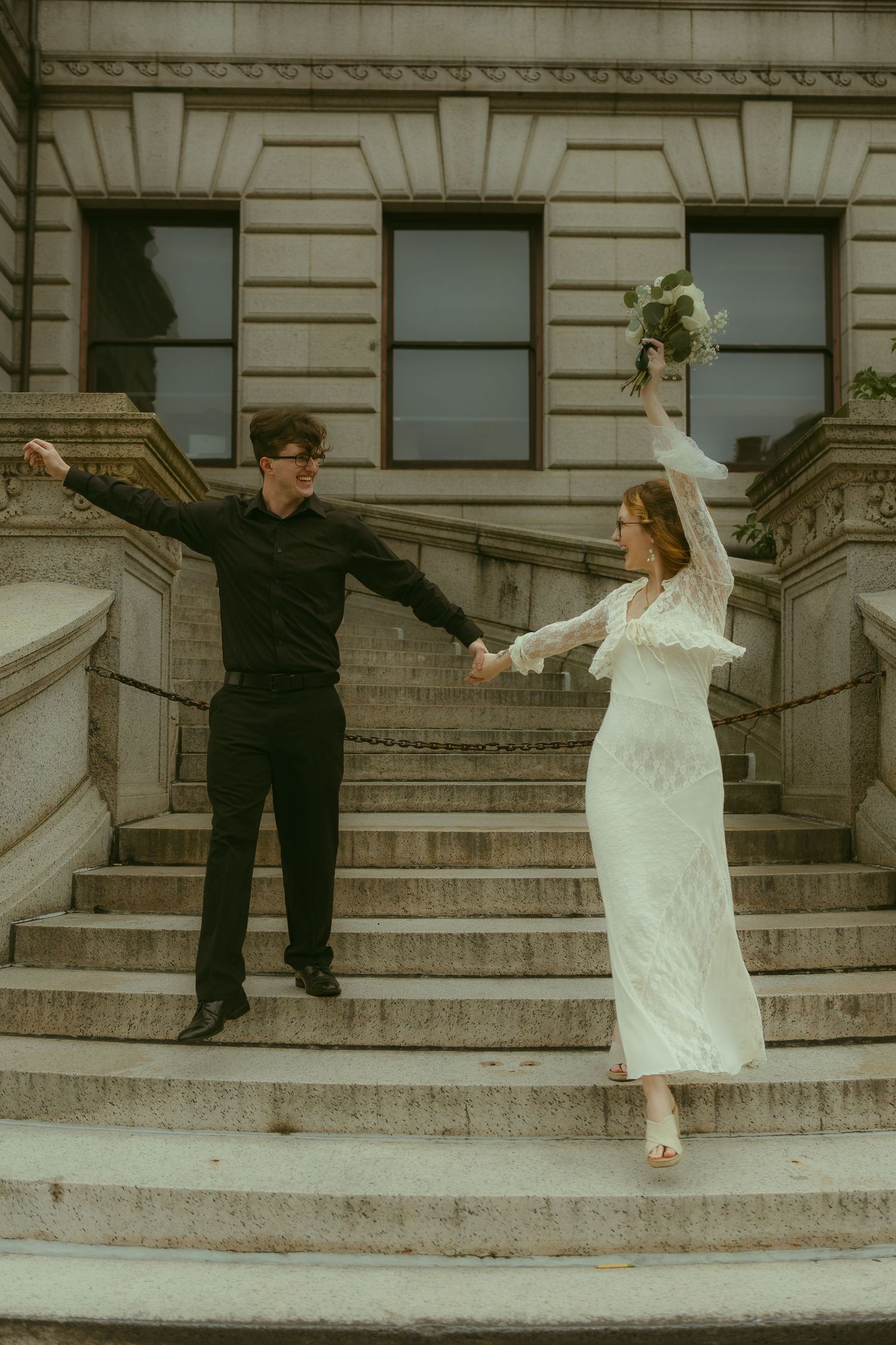 A couple performs a playful dance sequence on grand stone steps.