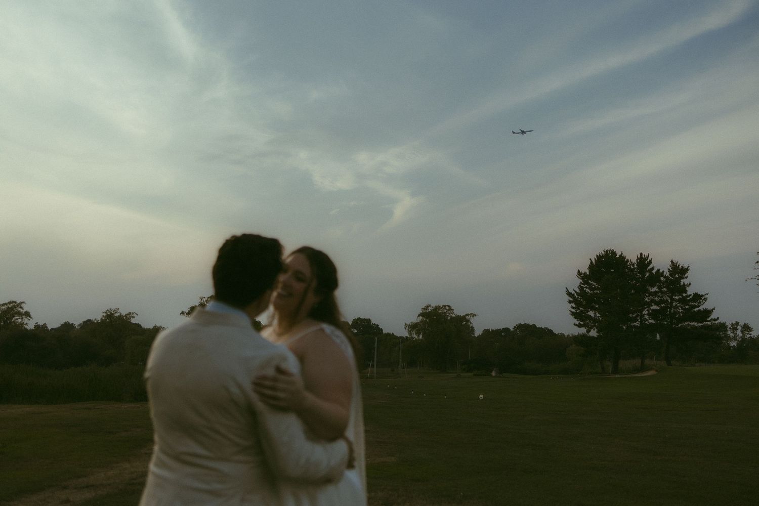 Silhouettes embracing in an open field during golden hour.