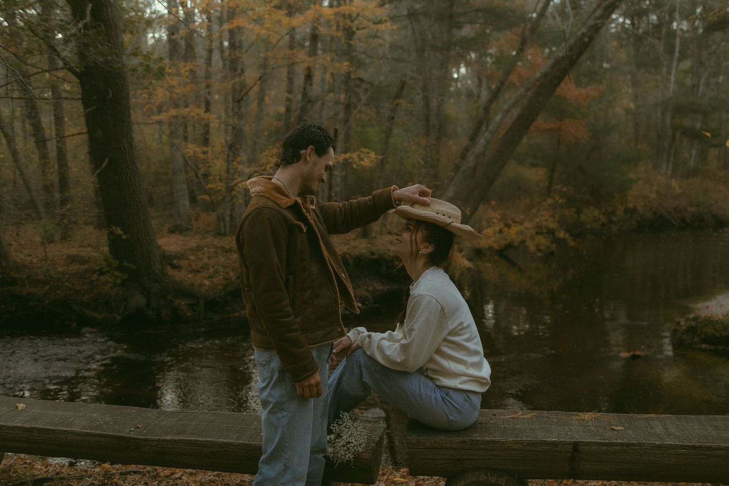People sit together on wooden benches in an autumn forest setting.