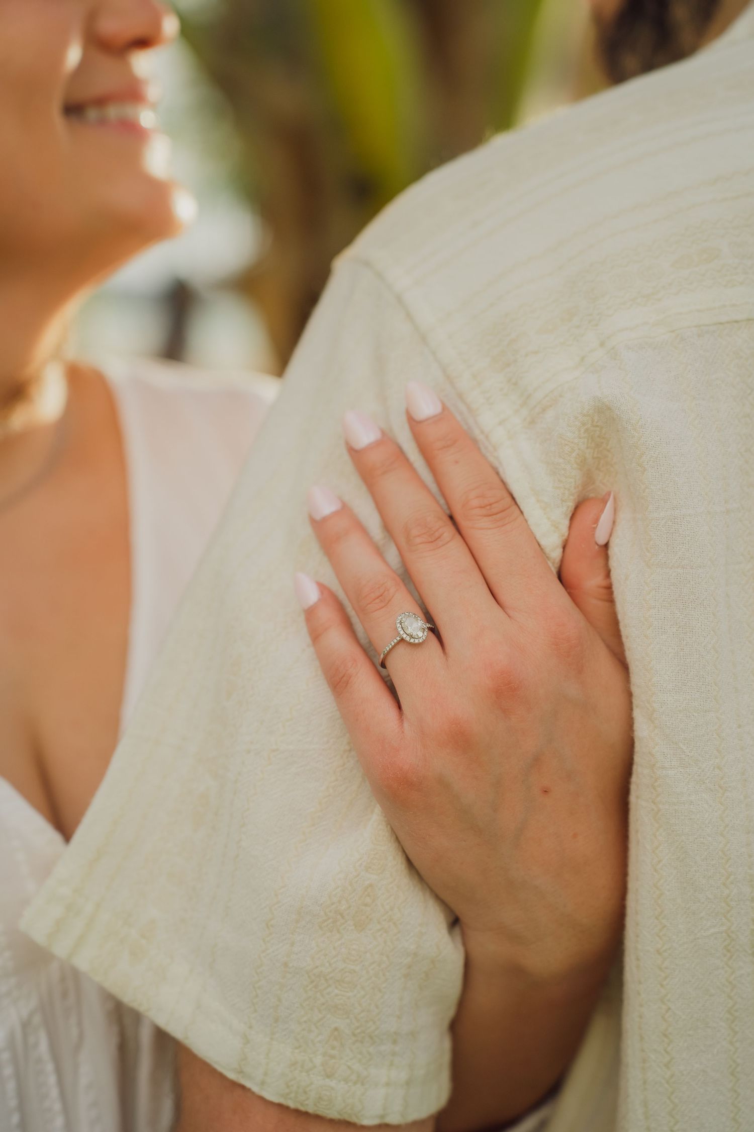 Close up view of hands wearing a wedding ring against white fabric in natural lighting.