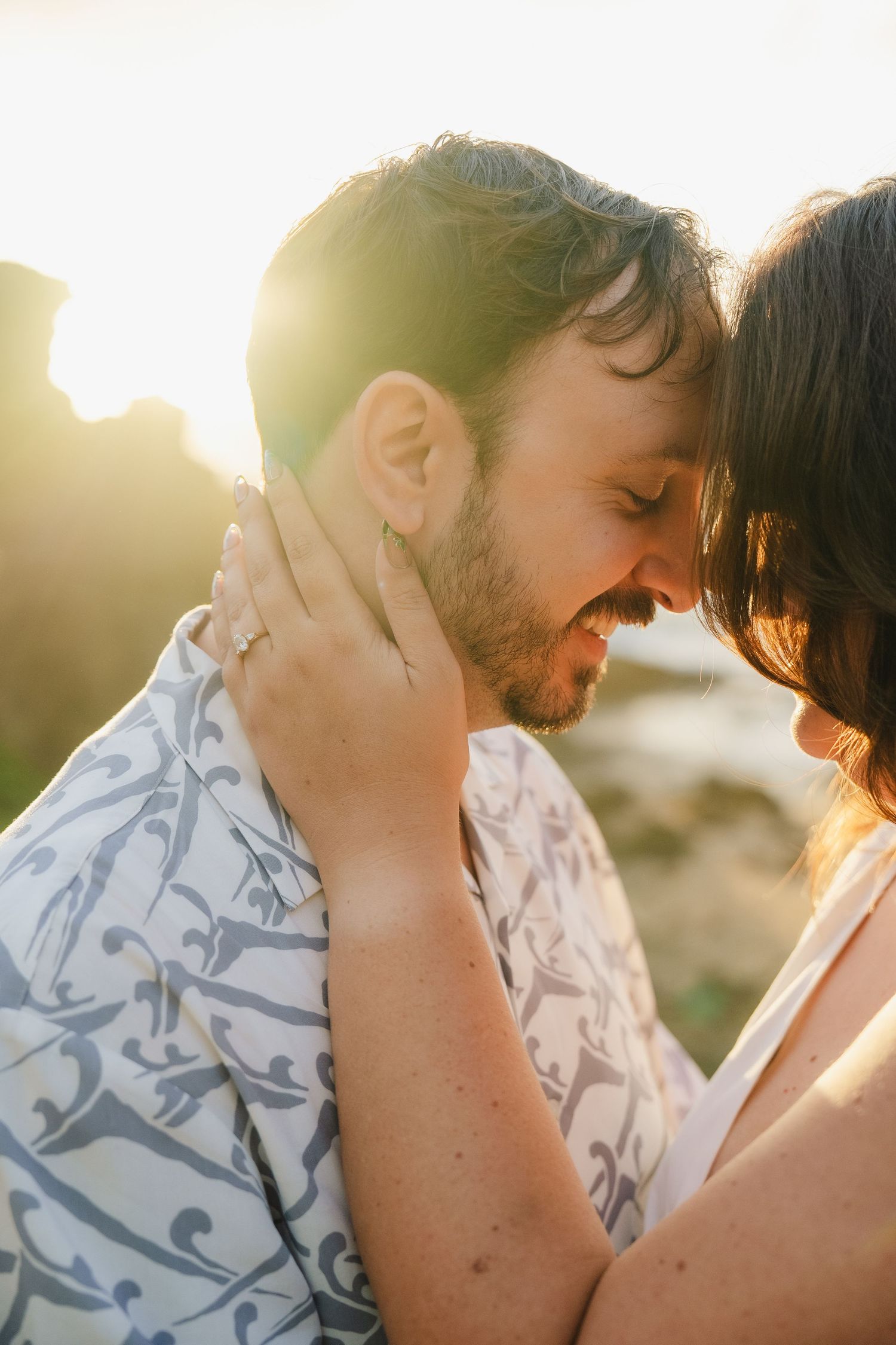 Romantic couple sharing an intimate moment at sunset with golden light streaming through as they embrace.