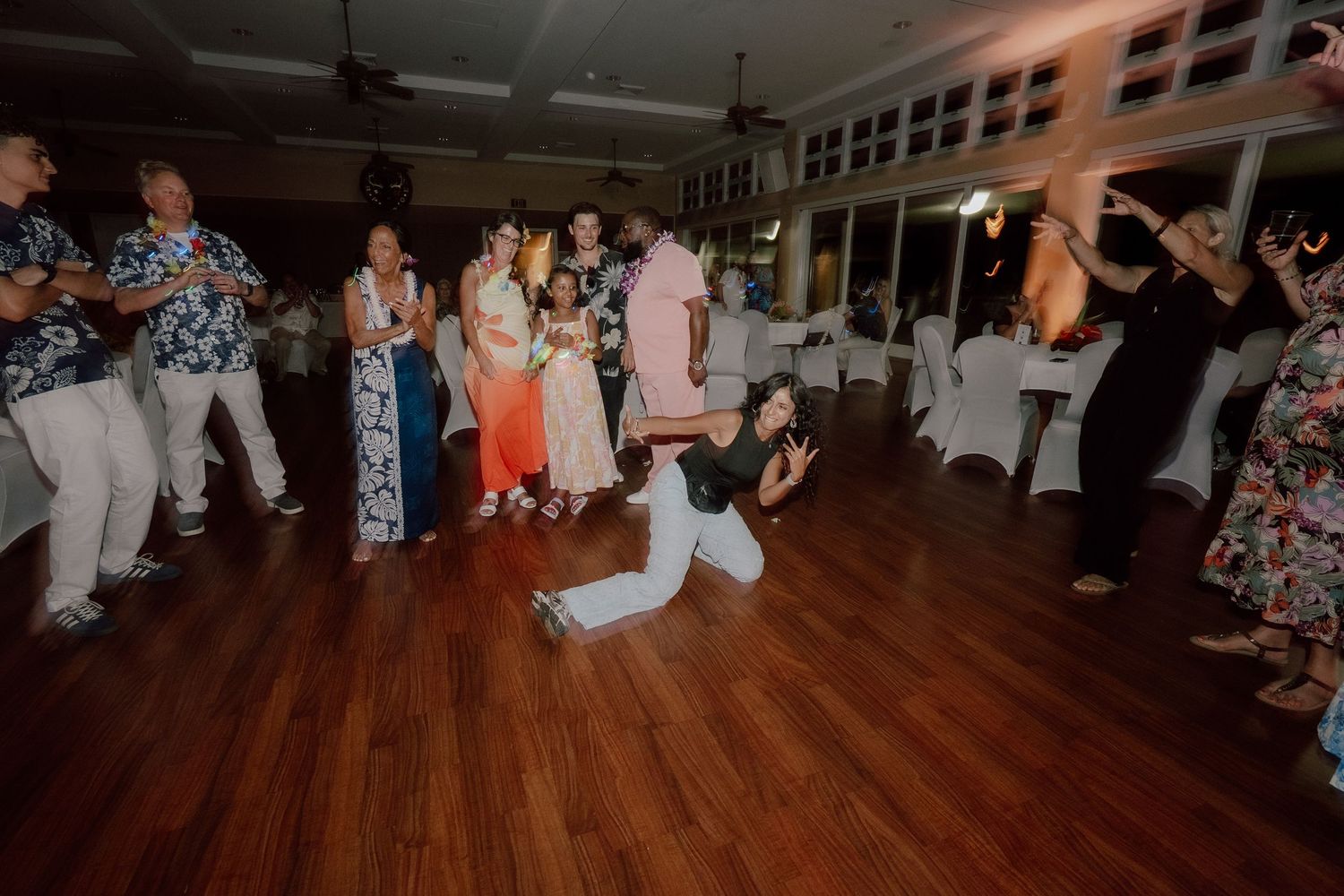 Wedding guests dance and celebrate on a wooden dance floor during an evening reception party.