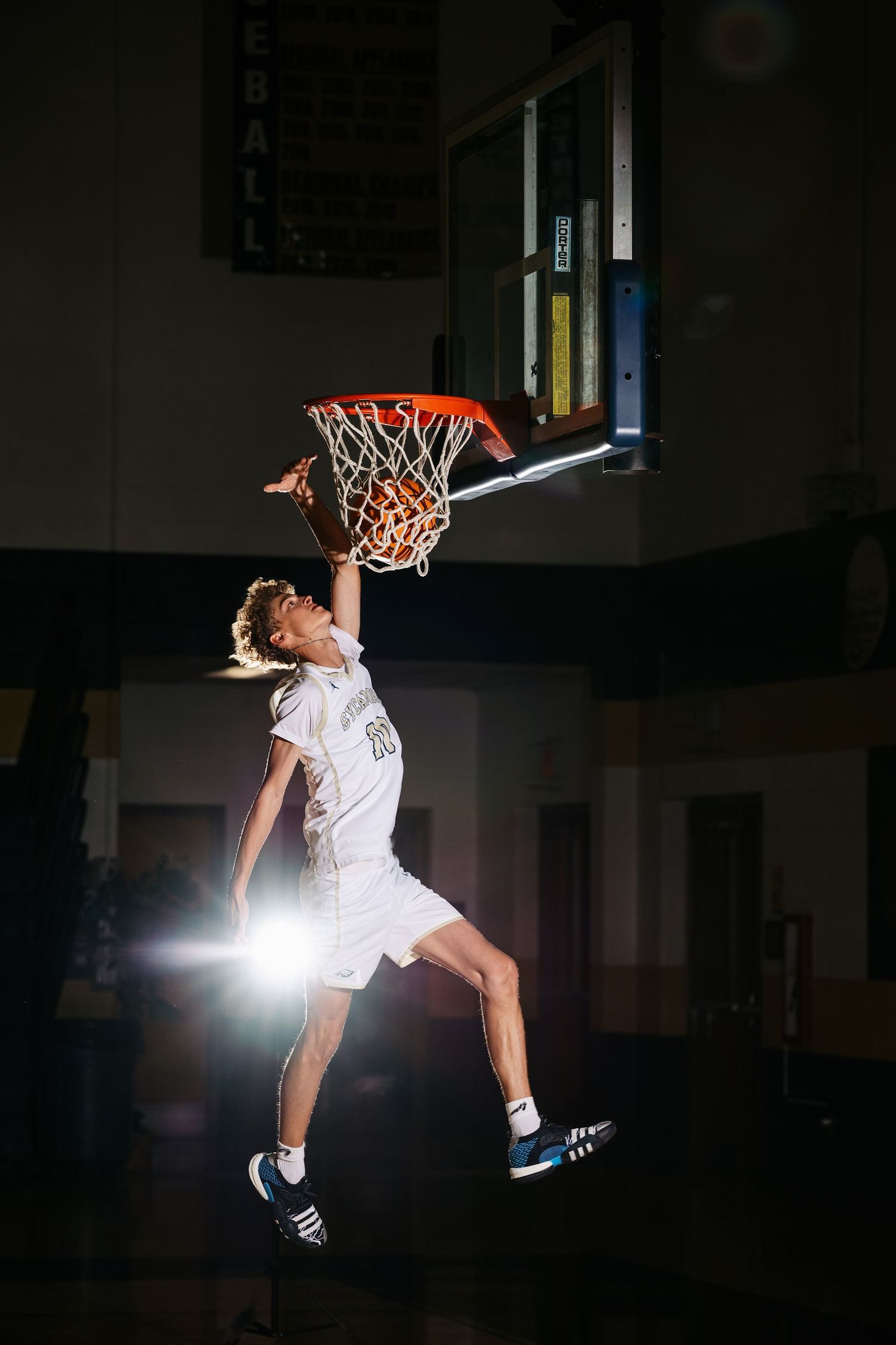 A basketball player performs an acrobatic slam dunk against a dark background in a dramatic sequence of action shots.
