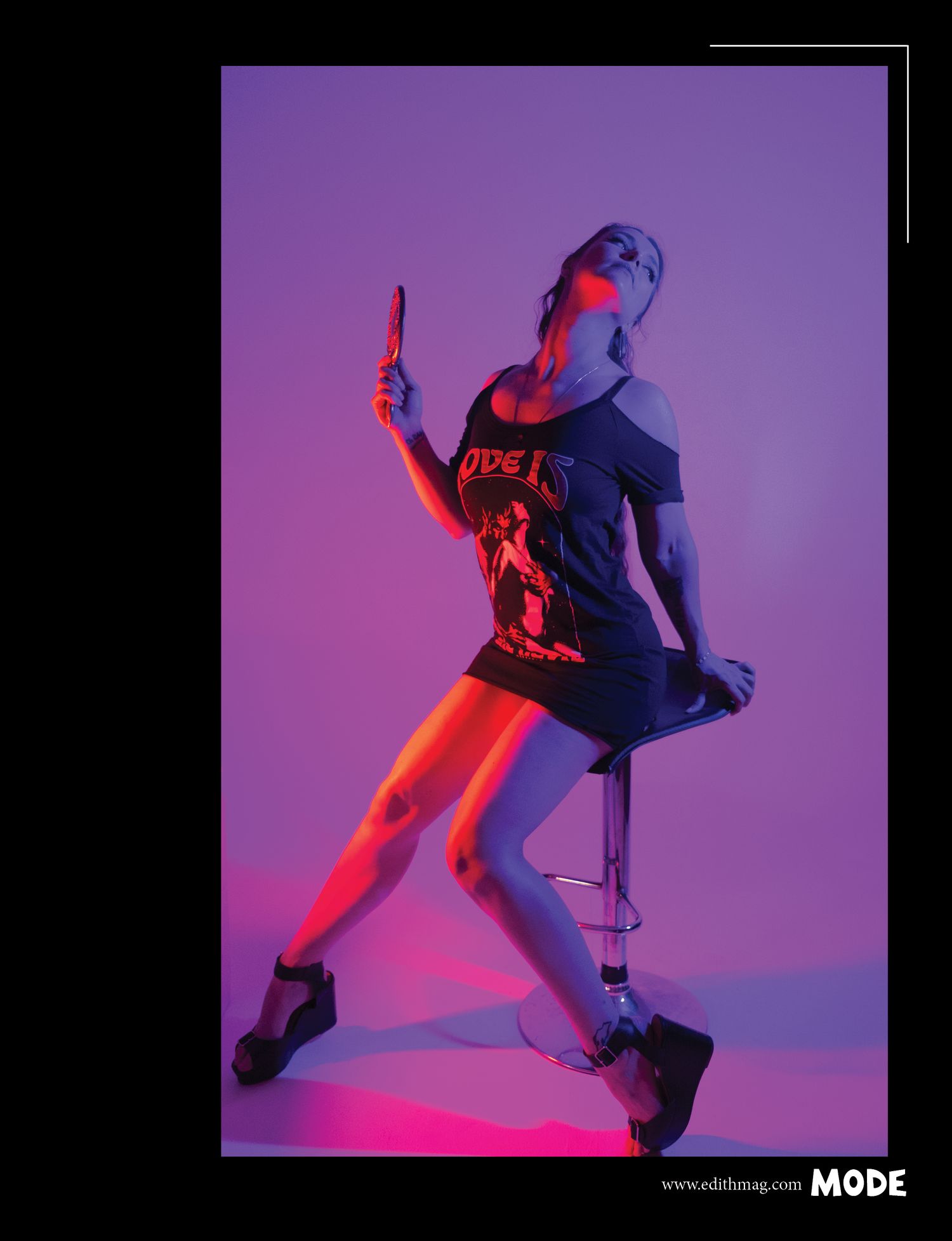 Dance-inspired fashion pose in purple lighting wearing graphic t-shirt.
