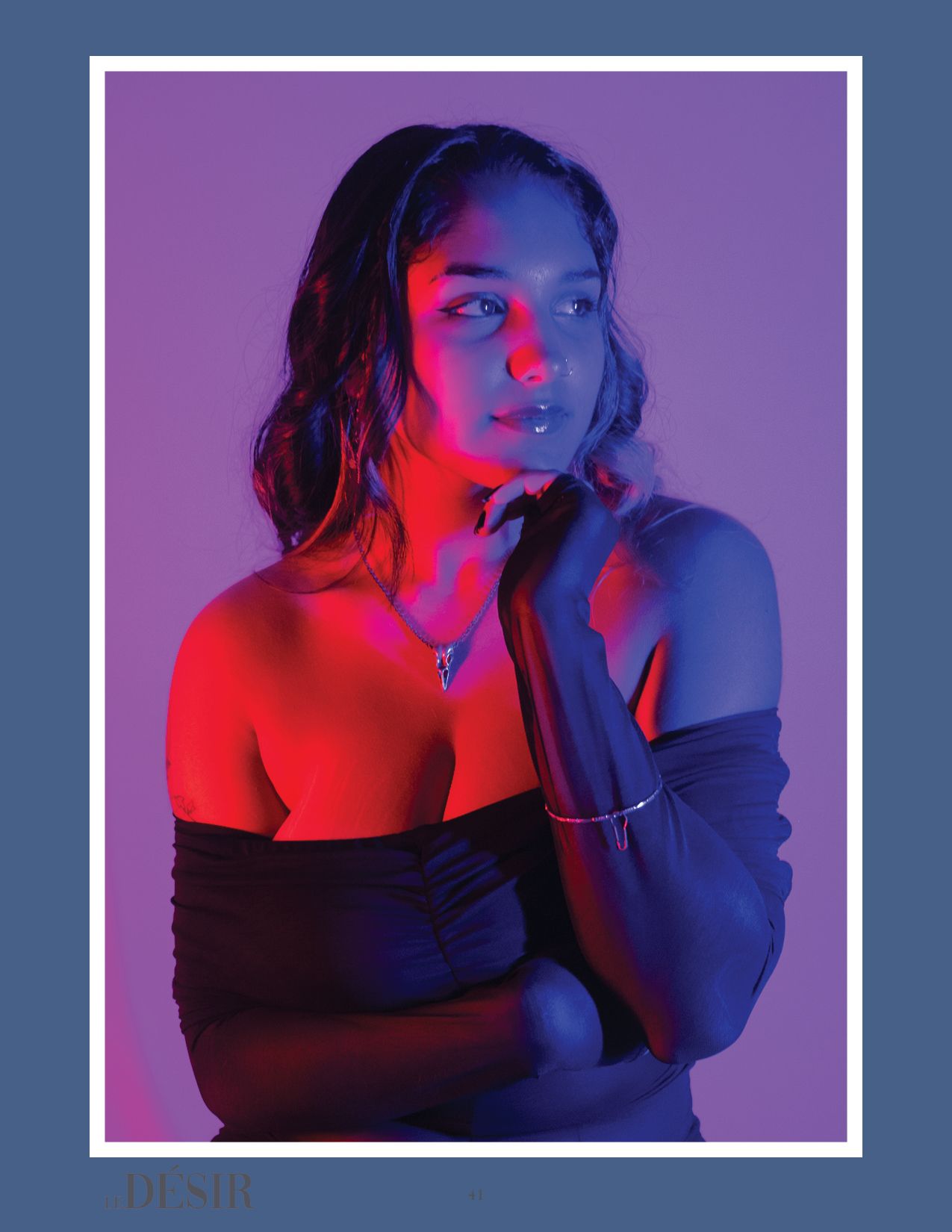 Model poses in off-shoulder dress with moody purple and red lighting effects.