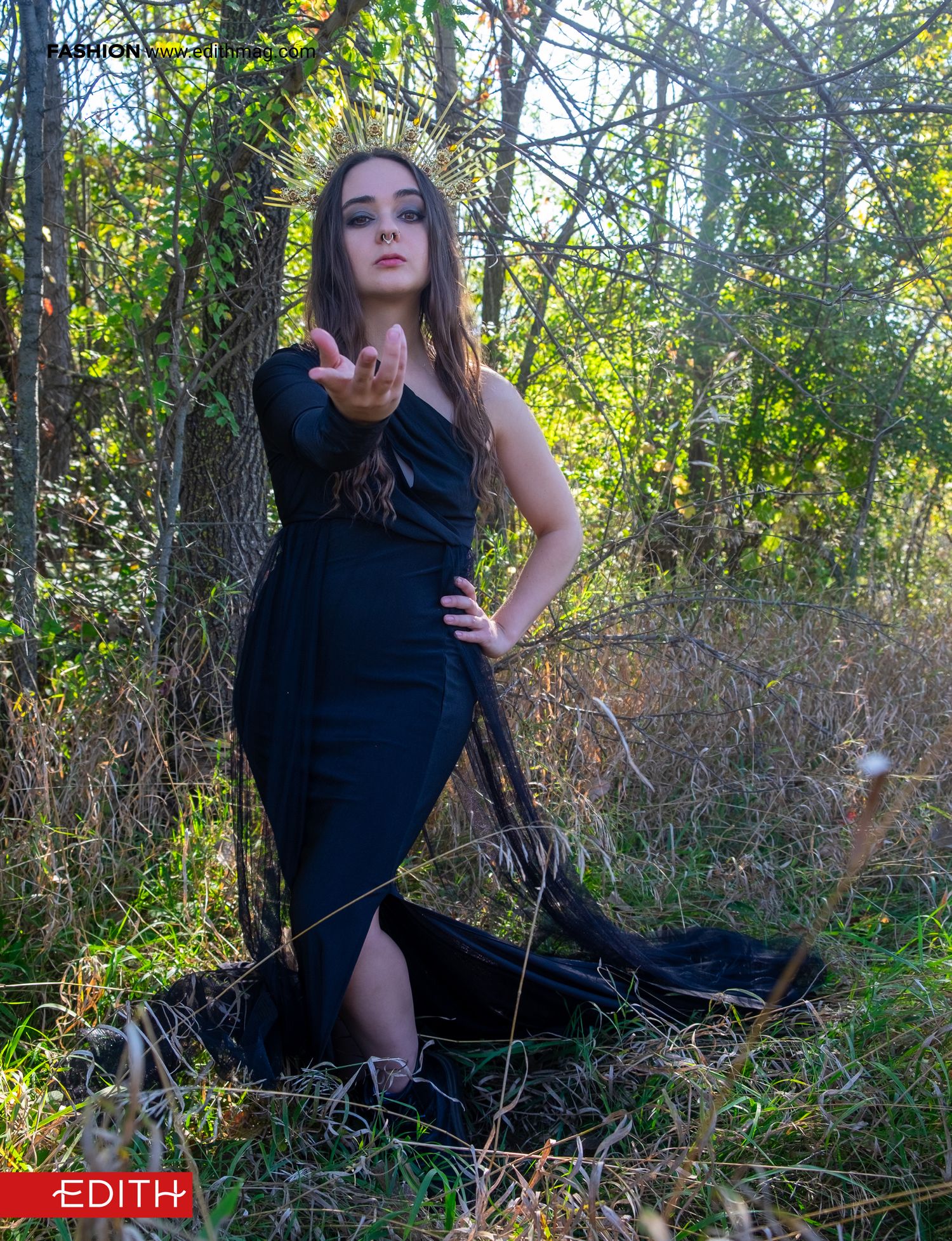 Dramatic fashion photo of long black dress against forest backdrop.