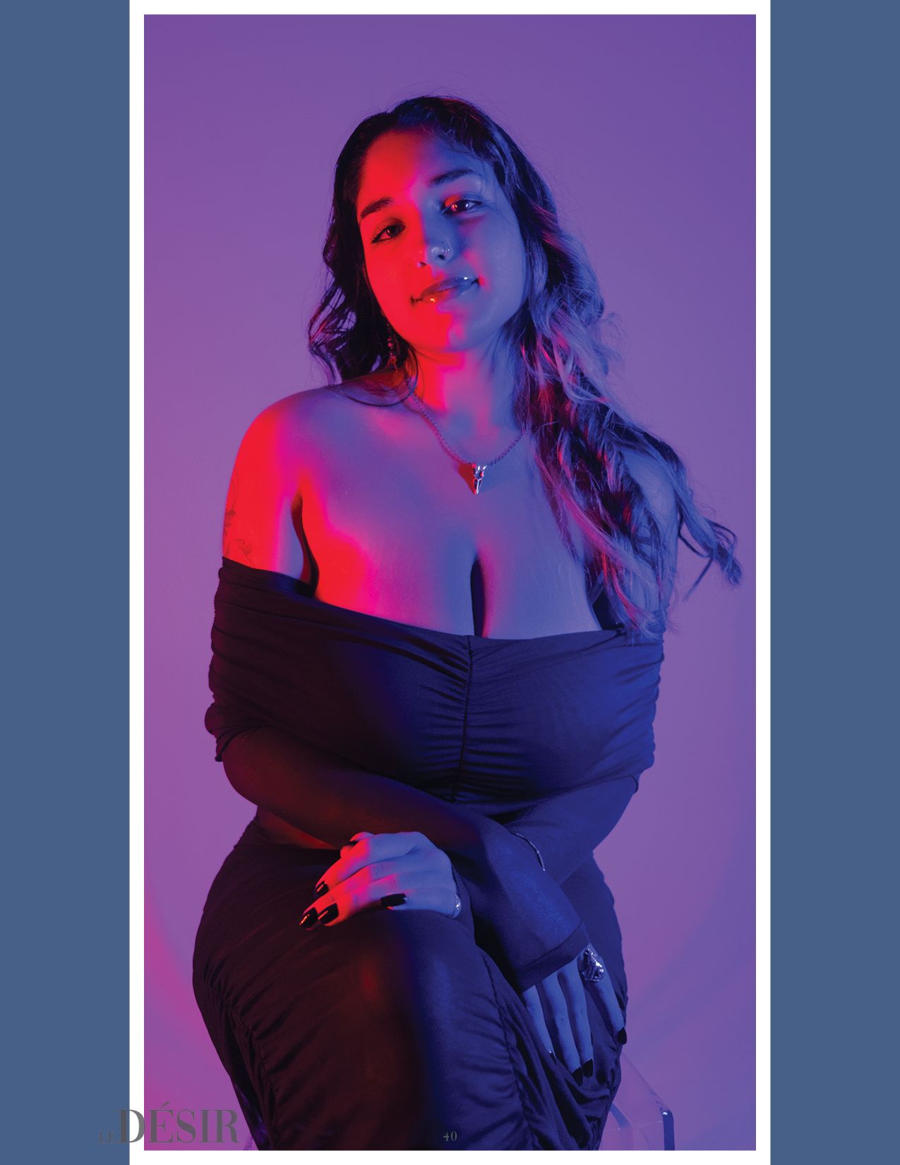 Dramatic fashion portrait with model in black dress against purple background with red lighting.