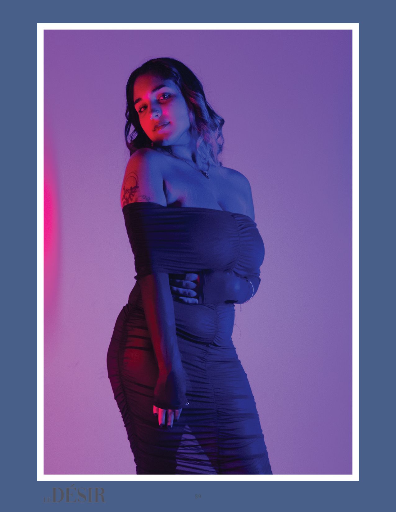 Fashion portrait with model in form-fitting dress against purple backdrop with red accent lighting.