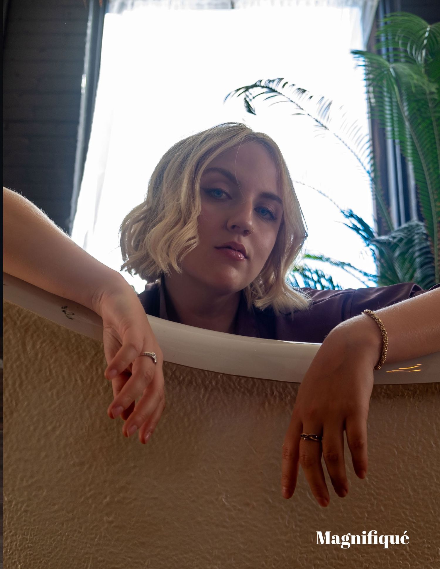 Artistic overhead portrait shot through white frame with houseplants visible.