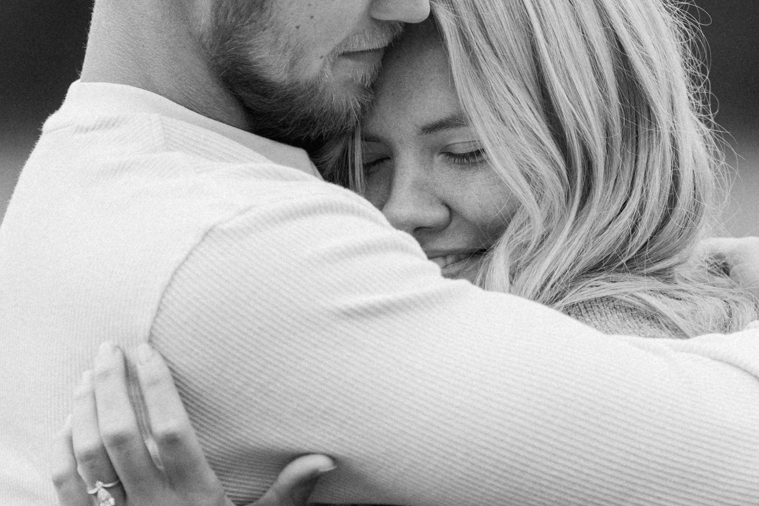 A tender black and white close-up of an intimate embrace showing affection and connection between two people.
