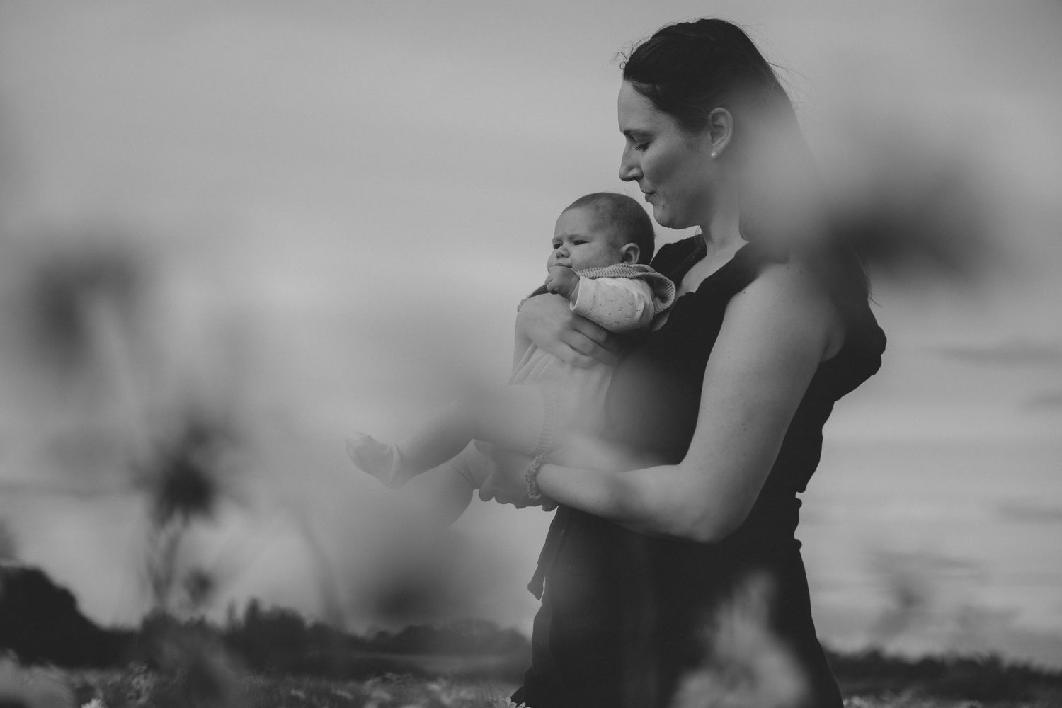 A dramatic black and white image of mother and child in a daisy field