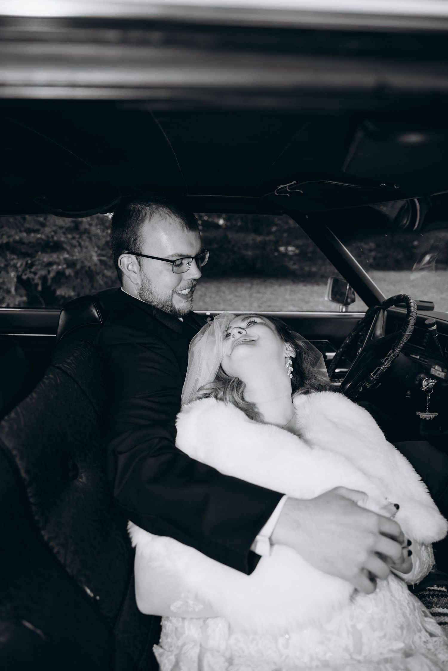 Vintage bride and groom portrait in old school car.