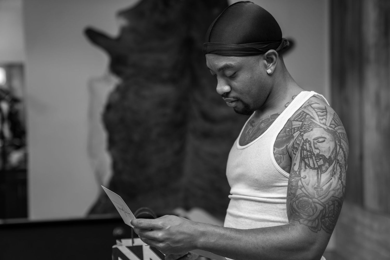 Black and white photo series showing tattoo artist working on client's arm in professional studio setting.