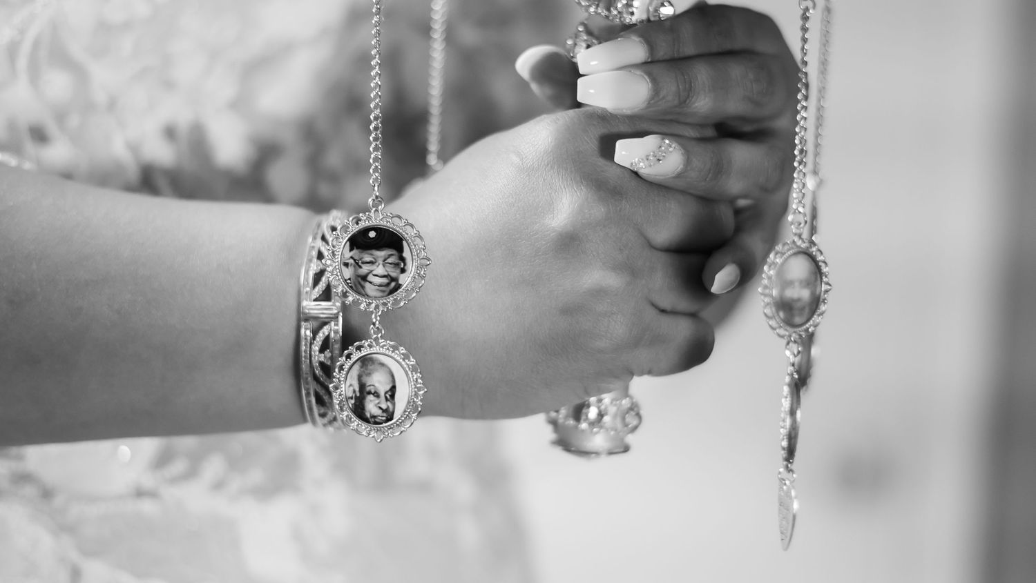 A close-up black and white photo of a hand wearing an ornate bracelet and ring with decorative details.
