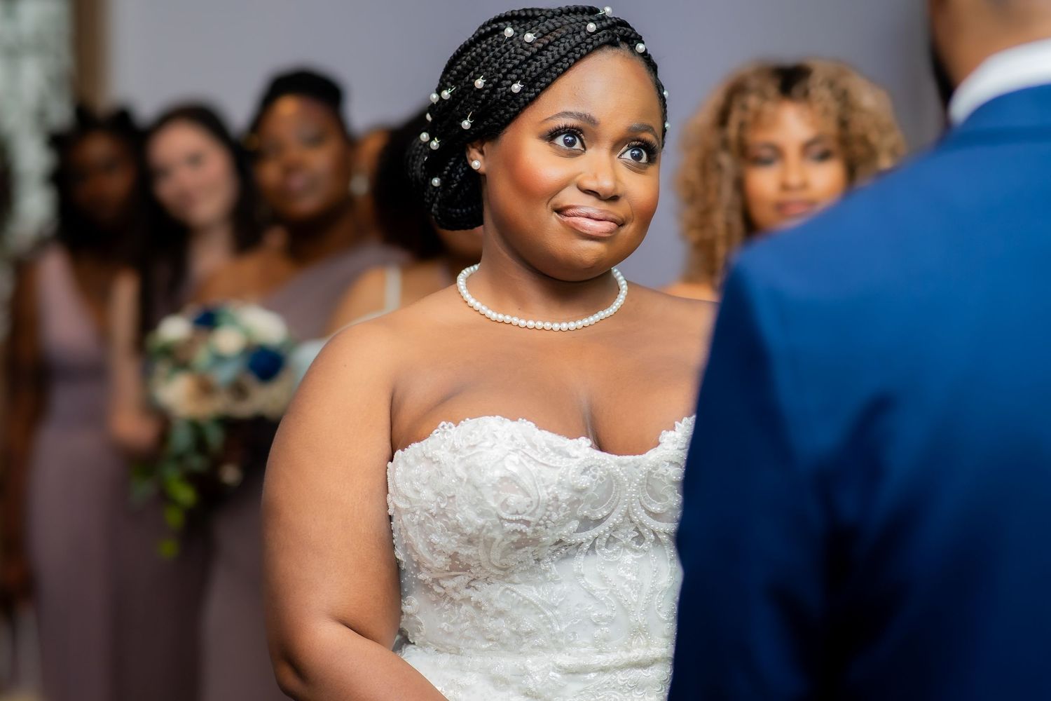 A bride in a sleeveless white gown smiles while dancing at her wedding reception.