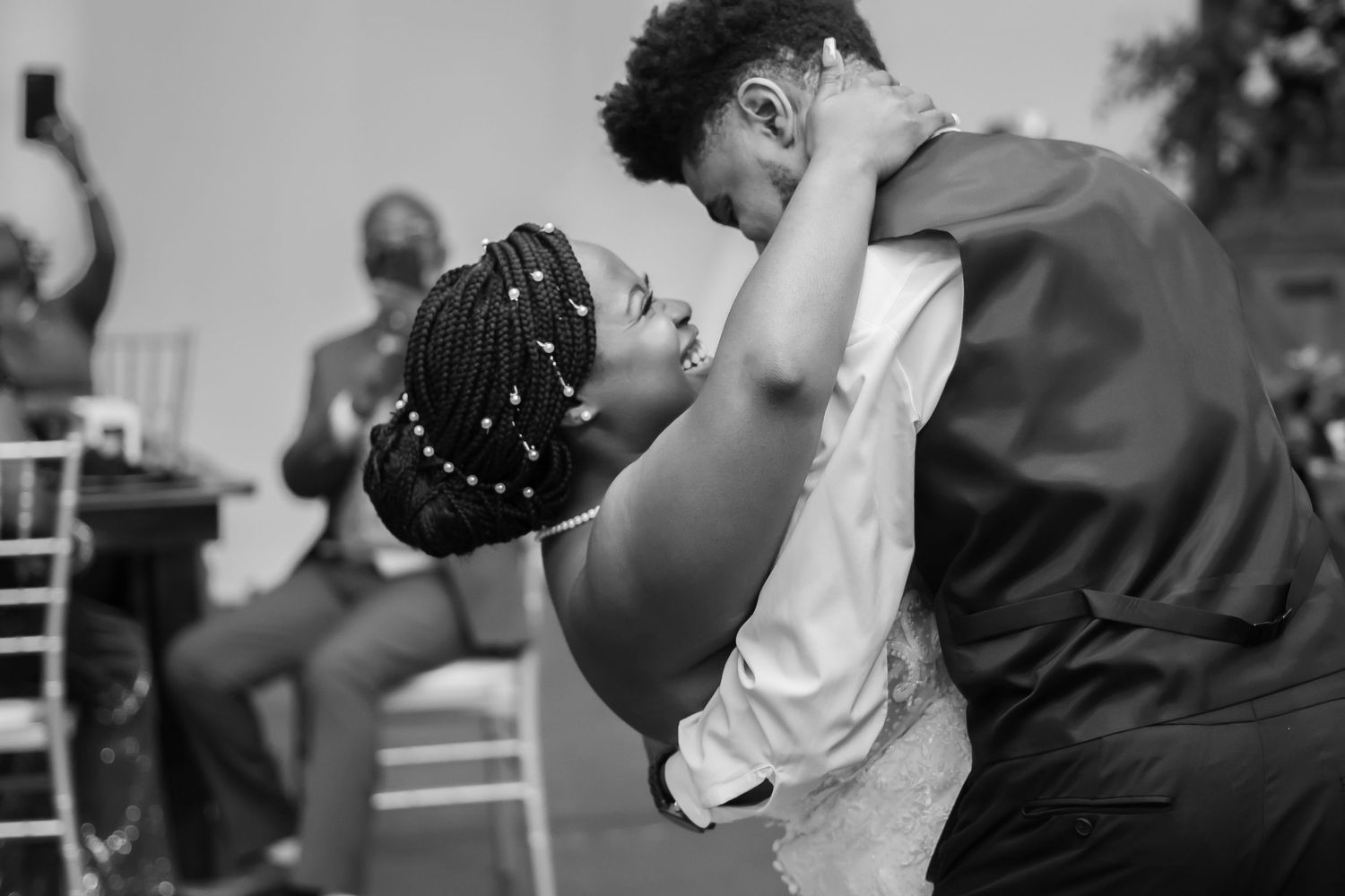 A romantic couple dances and embraces in an intimate black and white moment during a celebration.
