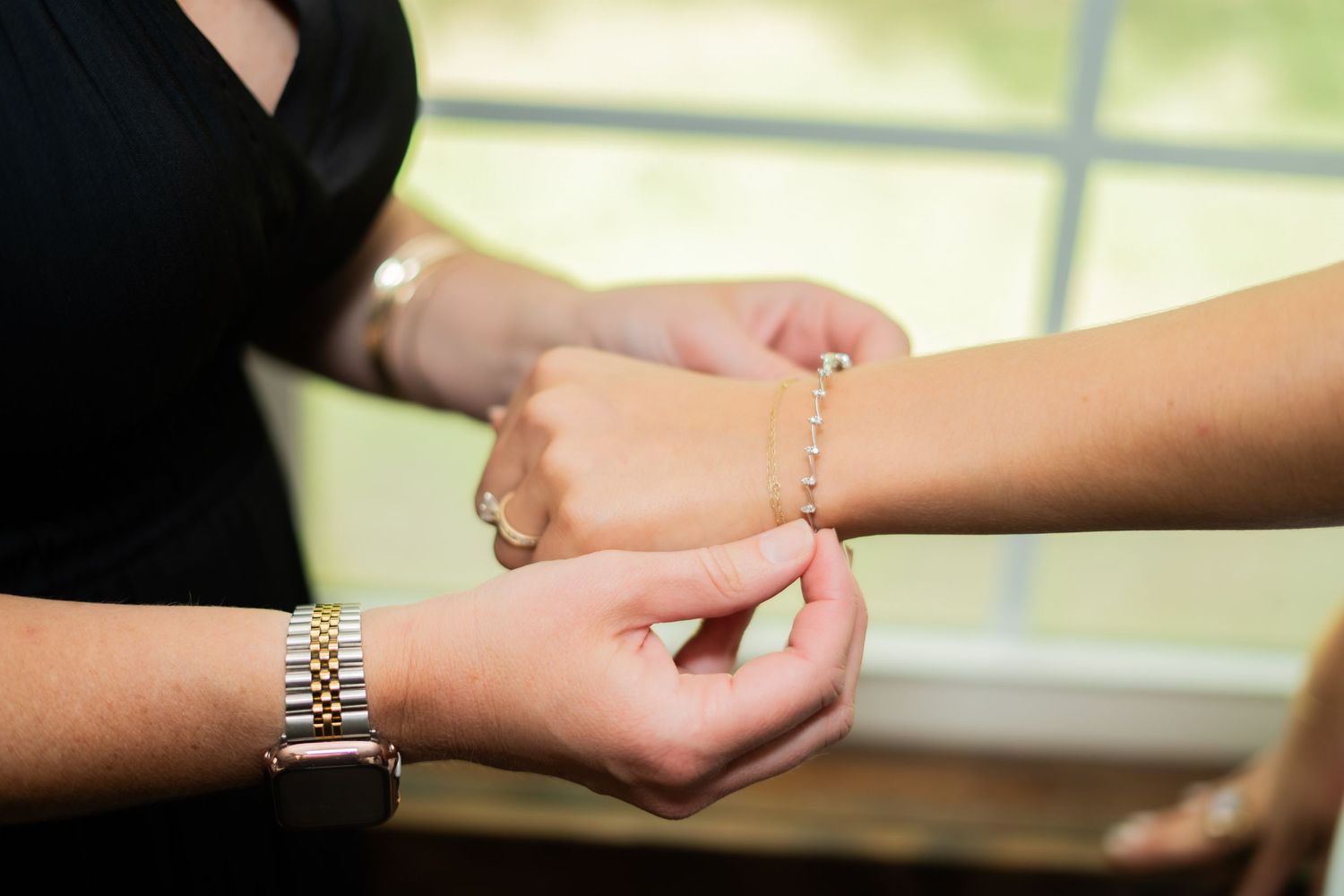 A person wearing a watch holds someone's wrist while reading palm lines in soft natural lighting.