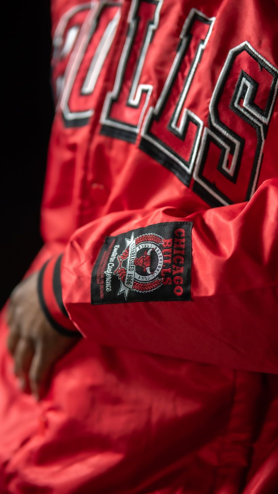Close-up detail of a red Bulls basketball jersey showing team lettering and anniversary patch.