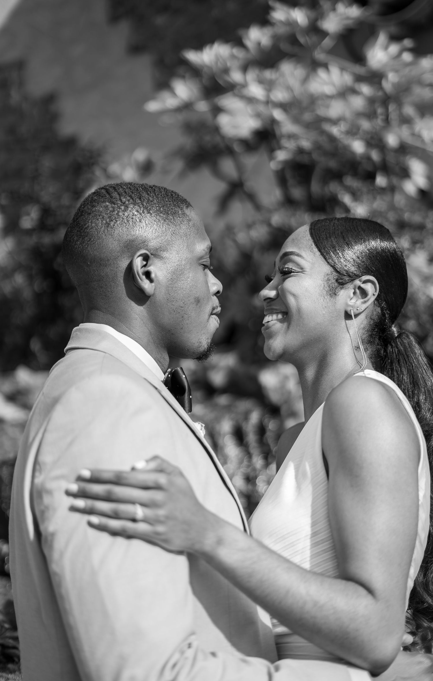 Black and white sequence of a couple sharing joyful laughter and embracing during a romantic outdoor moment.