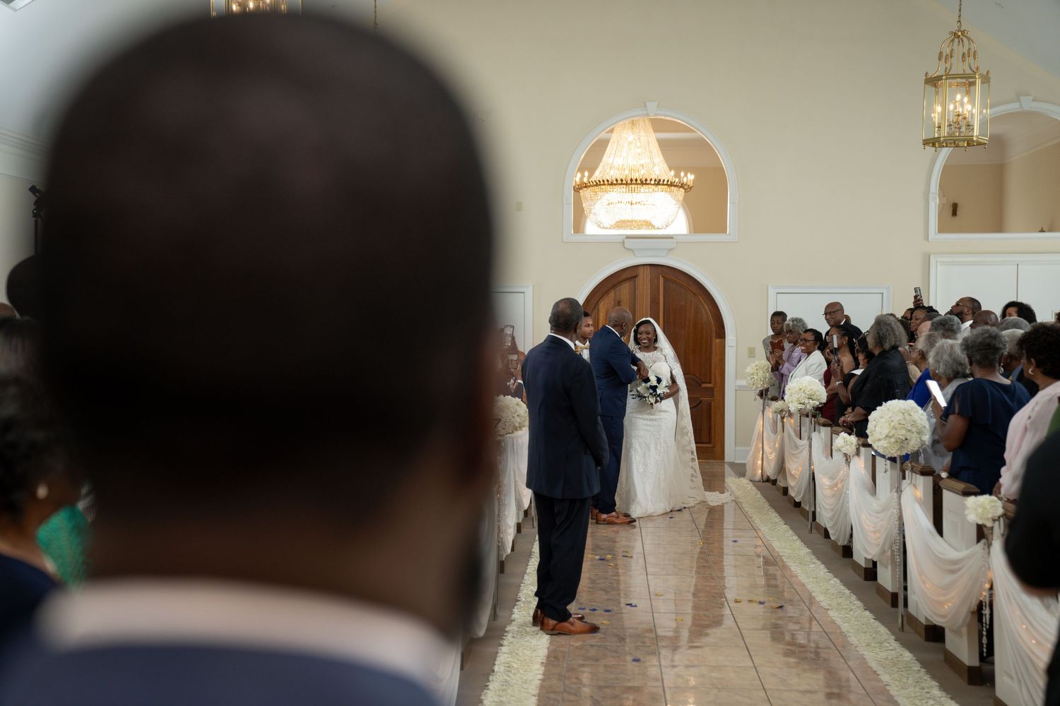 Wedding ceremony guests gathered in a church sanctuary as a couple walks down the aisle during the recessional.