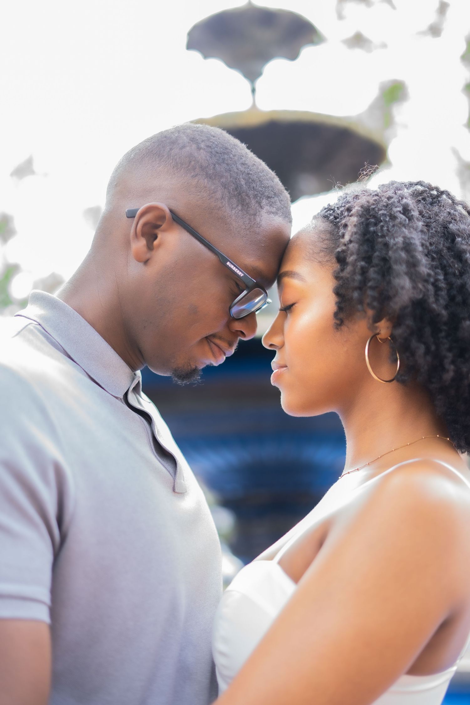 A romantic couple shares an intimate moment outdoors during a photo session with soft natural lighting.