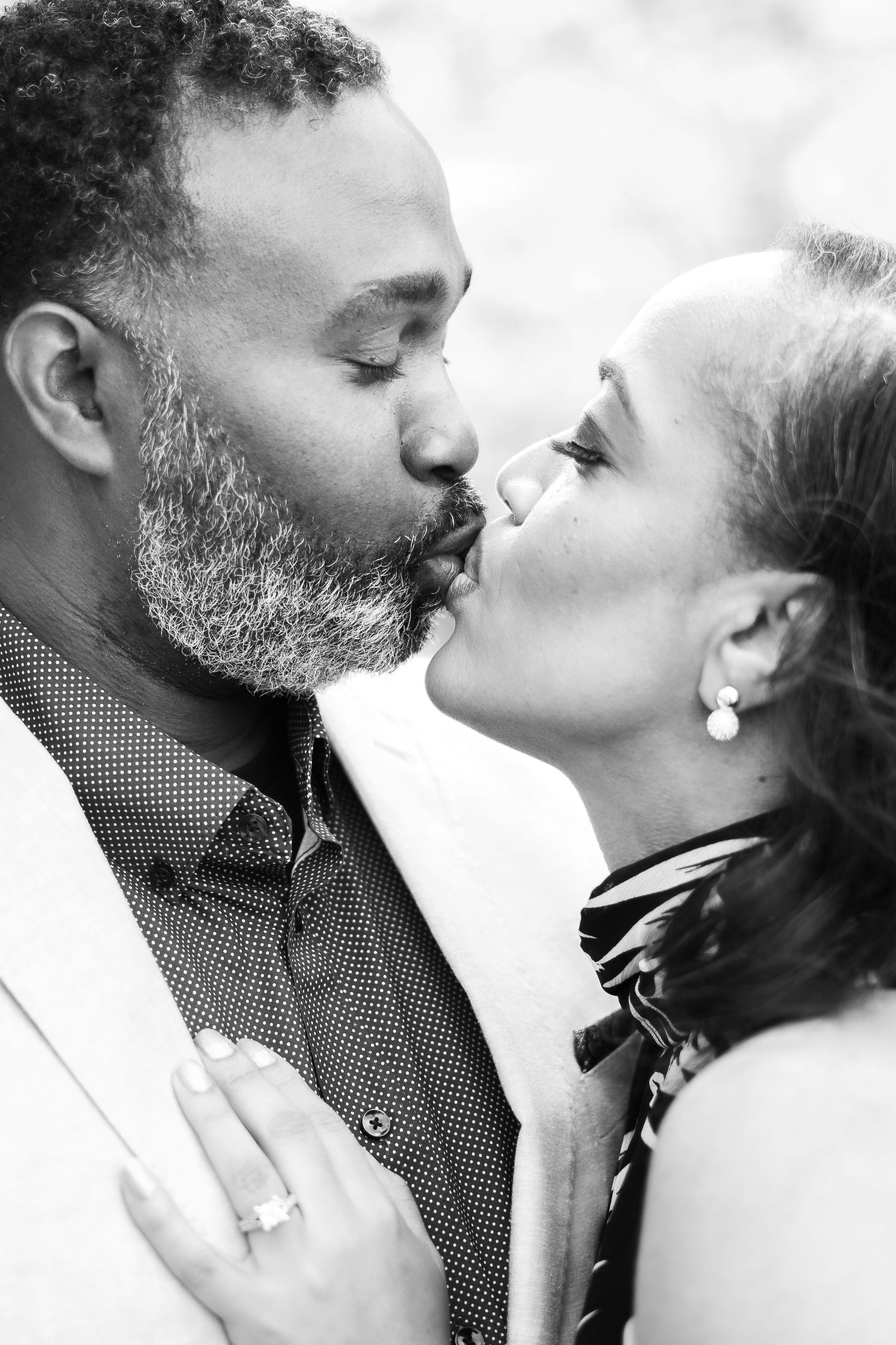An intimate black and white portrait of a couple sharing a romantic kiss.