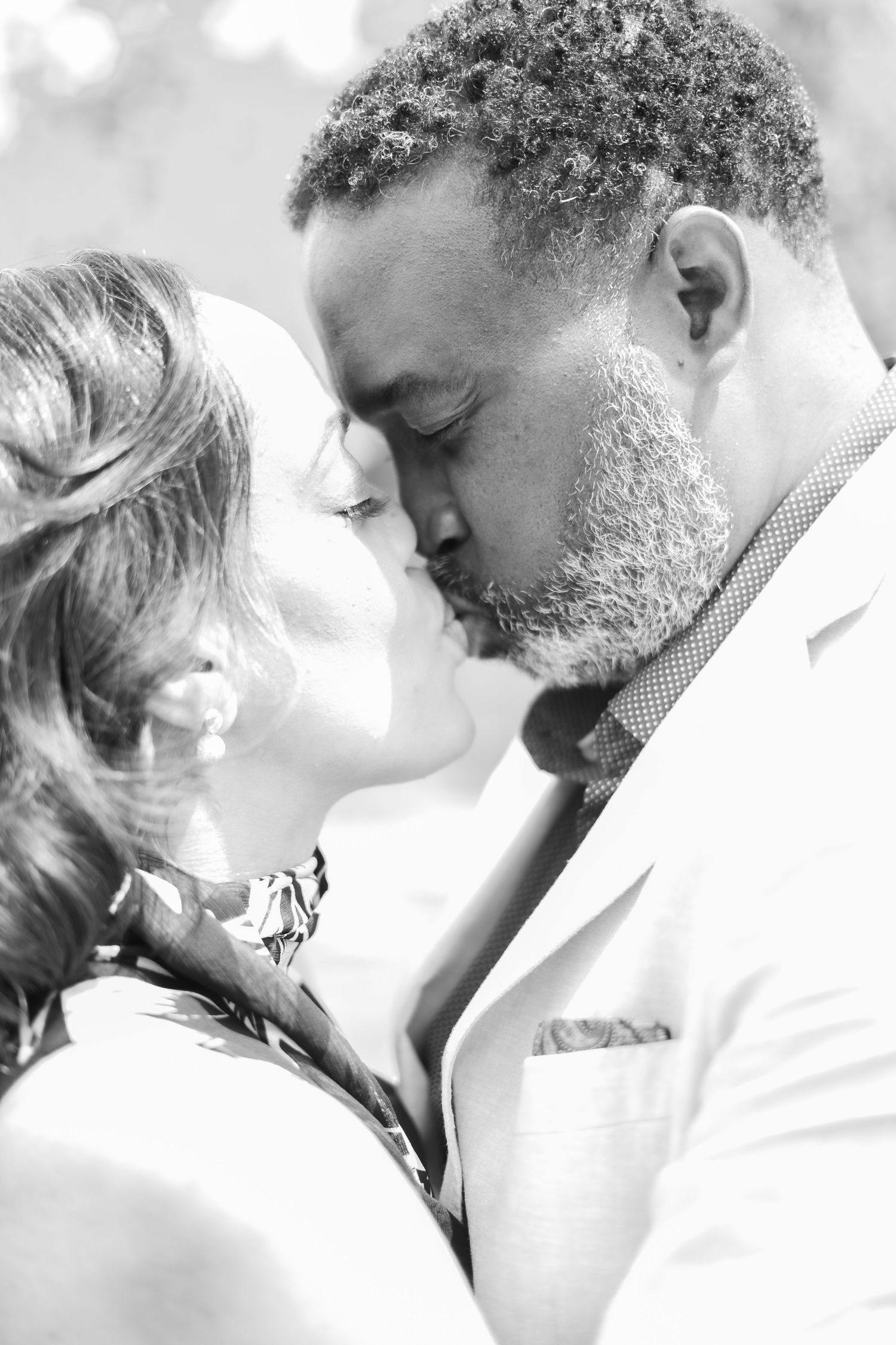 An intimate black and white portrait shows a couple in a tender moment.