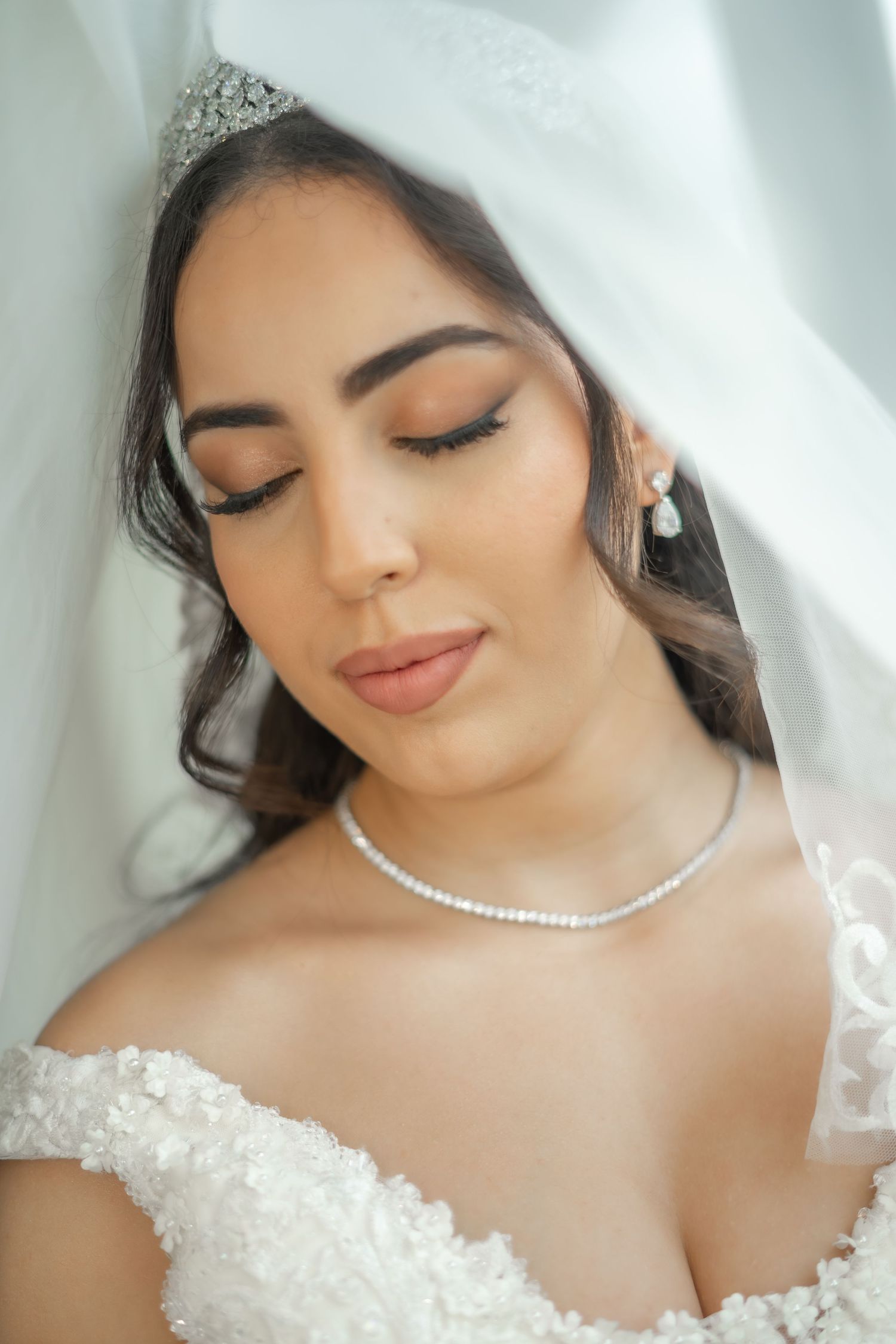 Bridal portrait showing delicate pearl necklace and lace wedding dress details with soft romantic makeup.