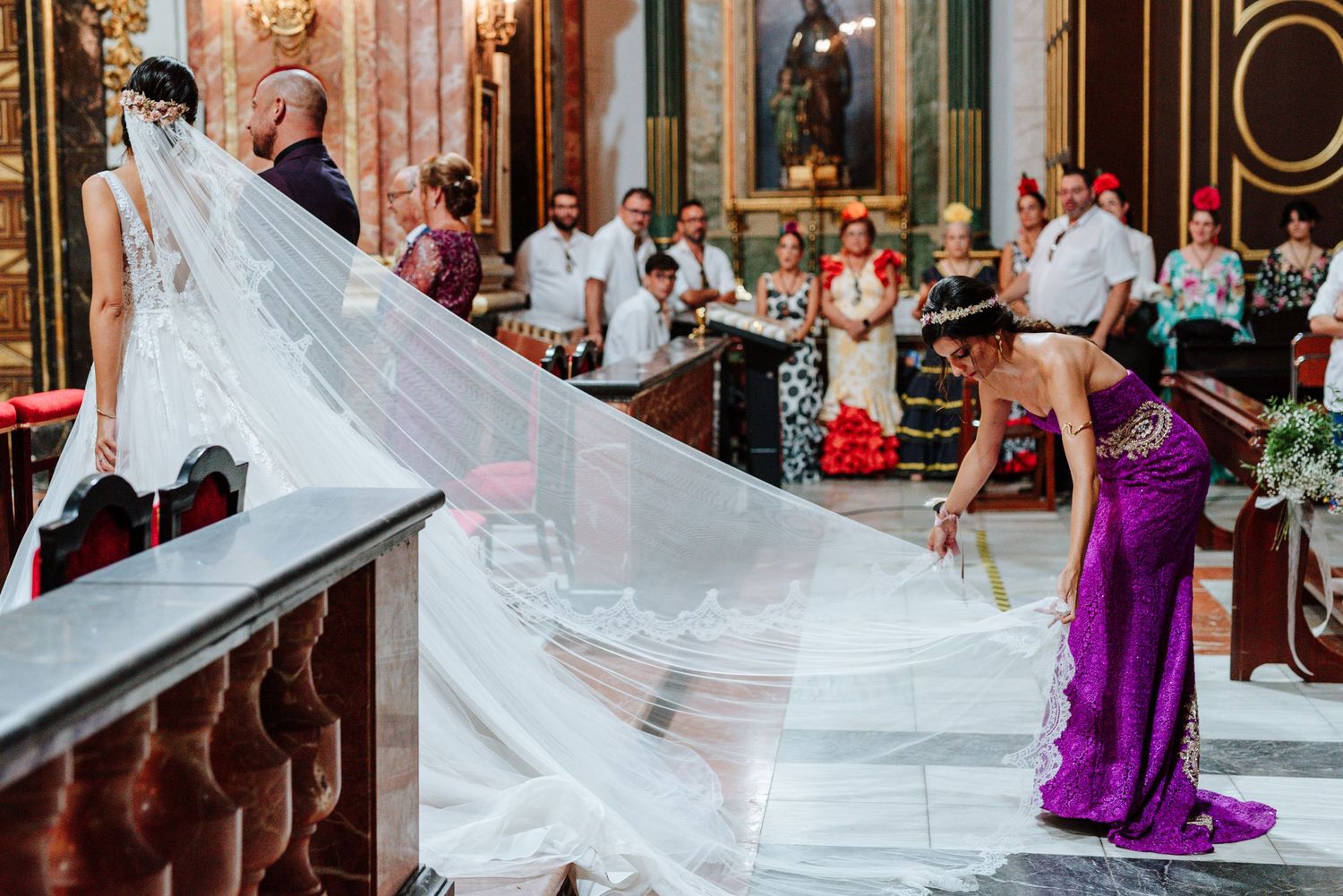 Detalle de la hermana de la novia acomodando el vestido durante la ceremonia en Nuestra Señora del Socorro de Aspe, Alicante.