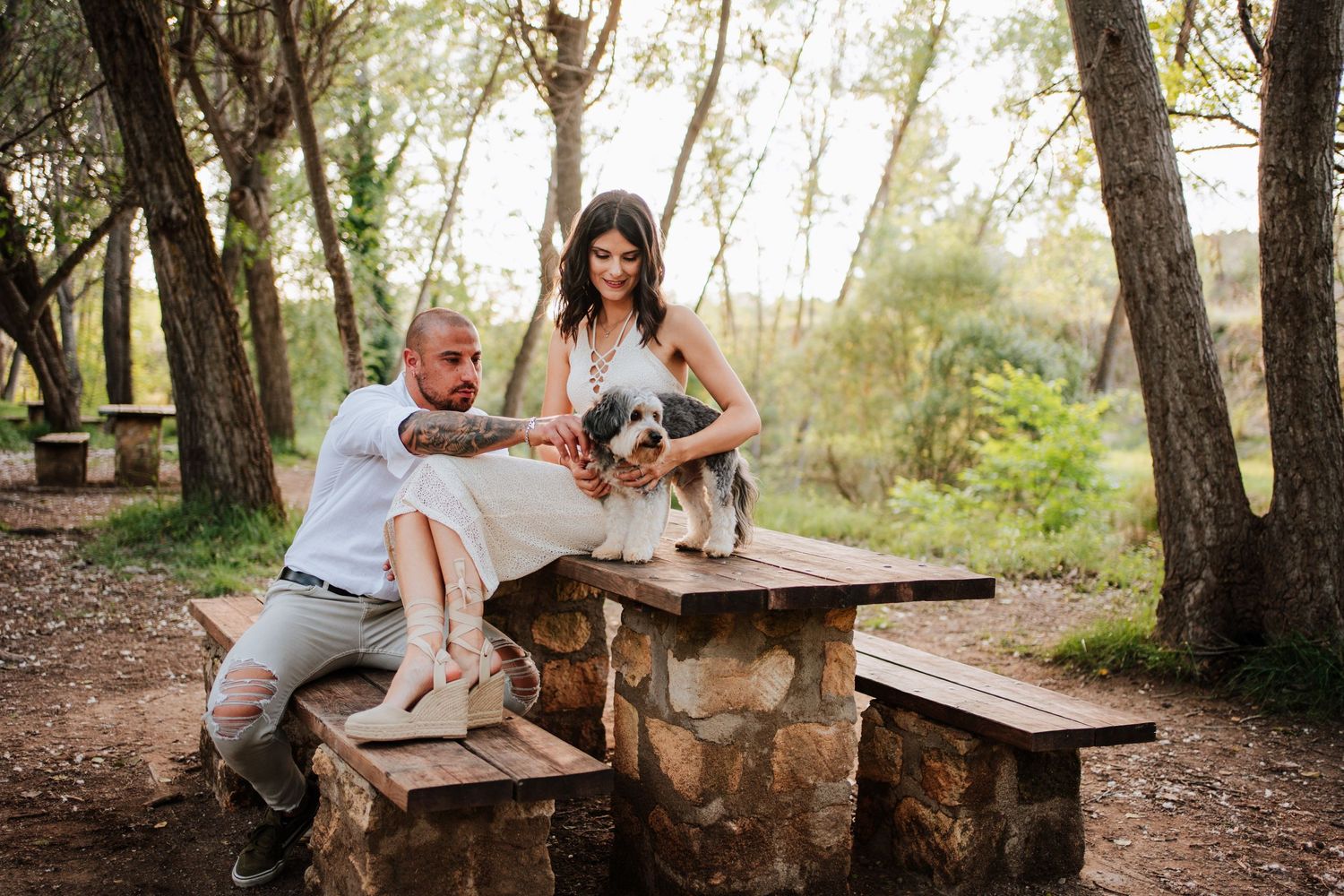 Pareja con su perrito Shih Tzu en una mesa de picnic en una escena familiar durante la sesión preboda en Banyeres de Mariola