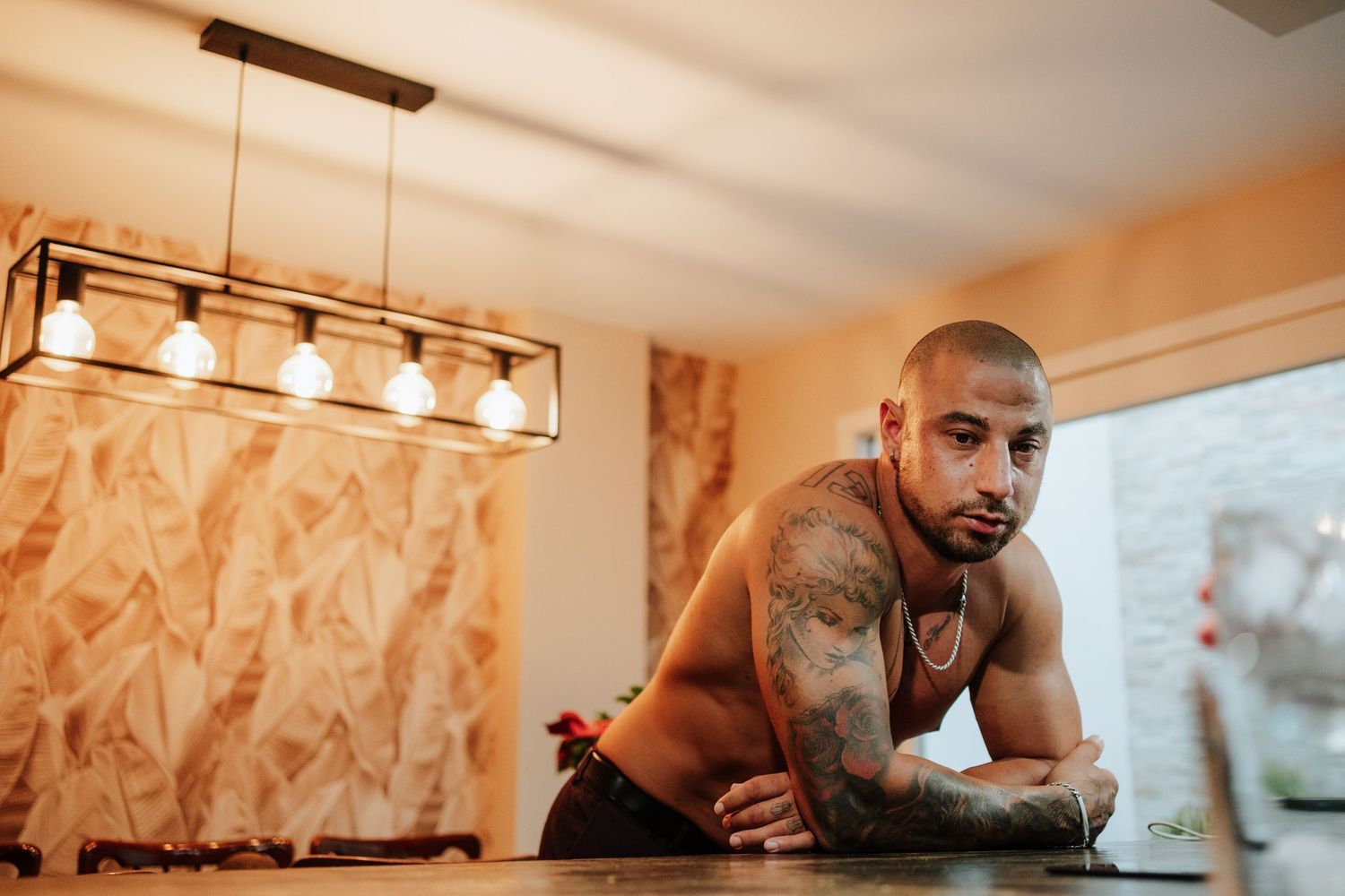 Novio sin camiseta relajado en la cocina de su casa.