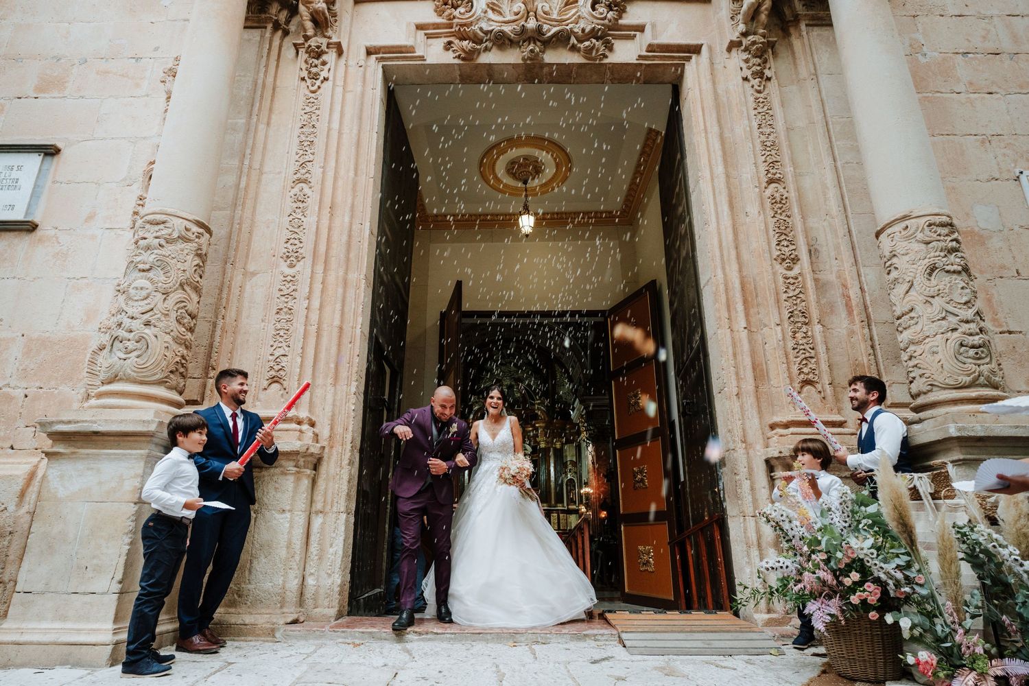 Salida de los novios de la Basílica de Nuestra Señora del Socorro de Aspe, los invitados lanzan unos cañones de confetti.