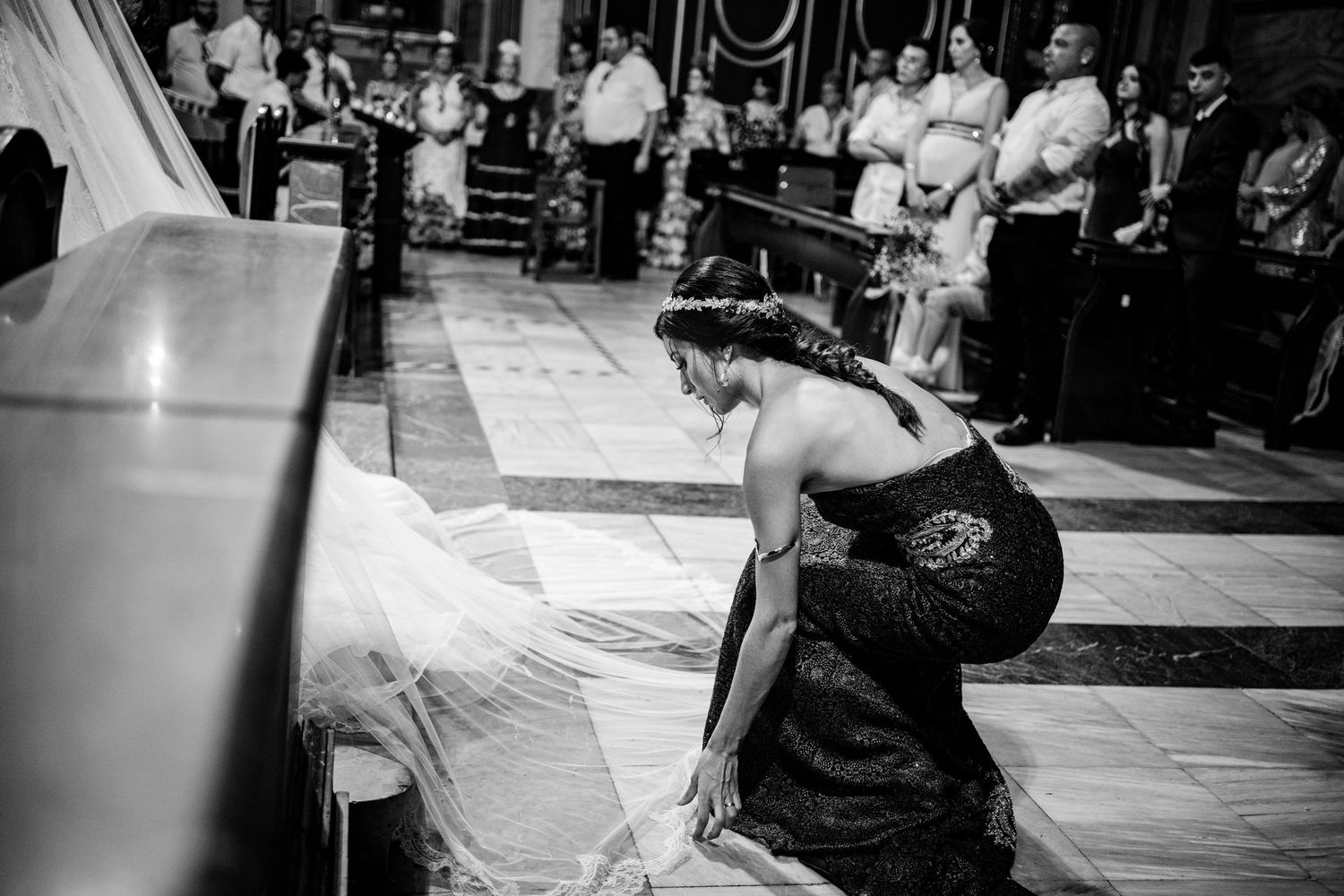 Detalle de la hermana de la novia acomodando el vestido durante la ceremonia en Nuestra Señora del Socorro de Aspe, Alicante.