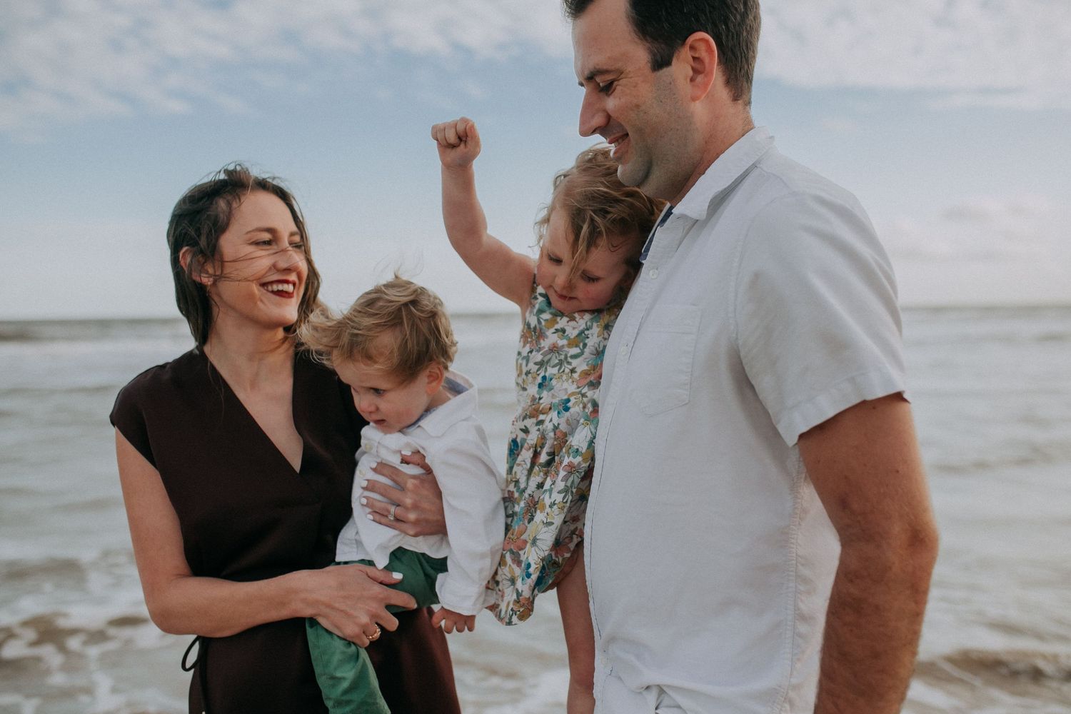 Family sharing joyful moments together on a cloudy beach.