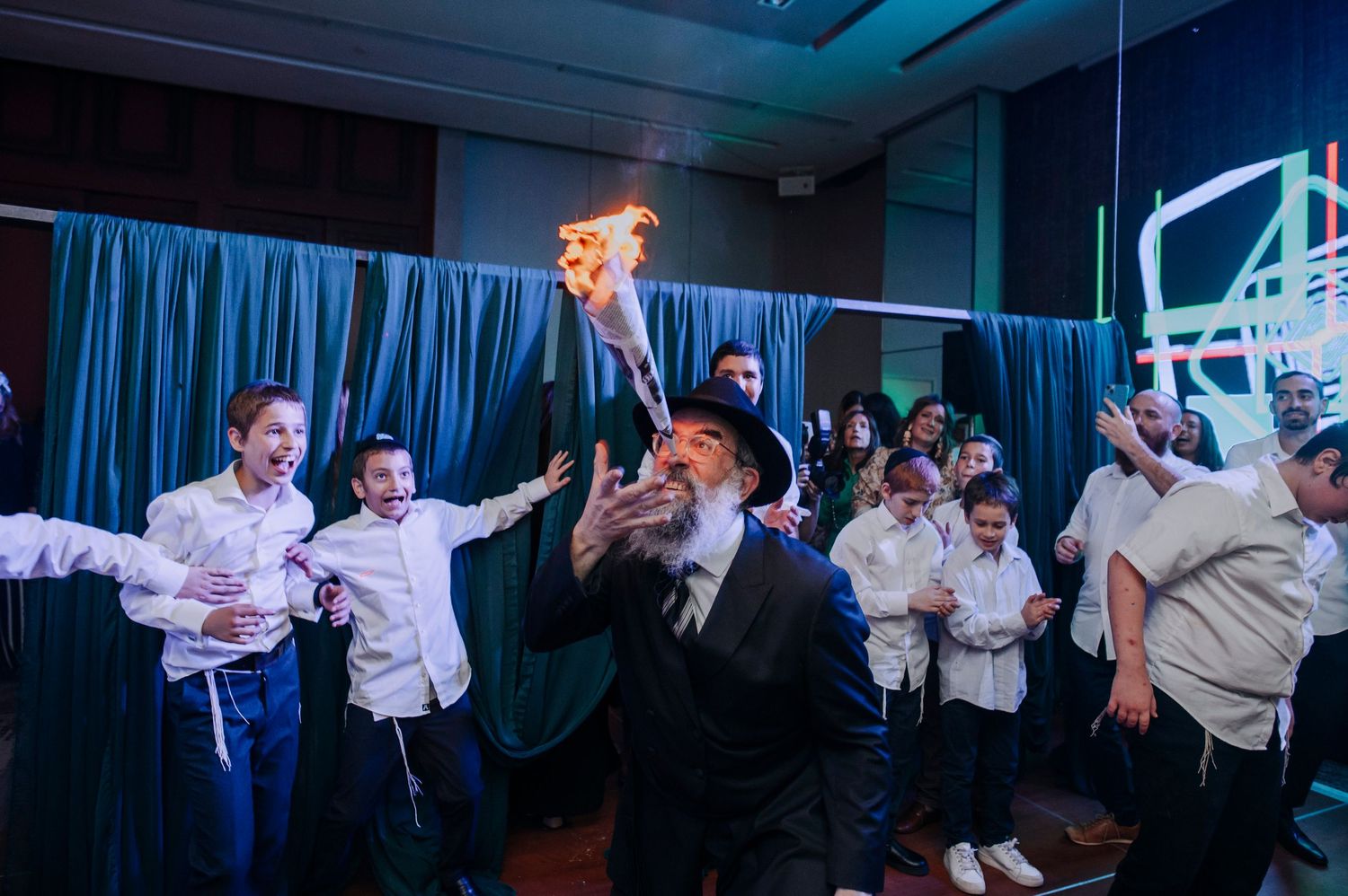 Lively celebration with dancing and revelry under blue lighting at an indoor event.