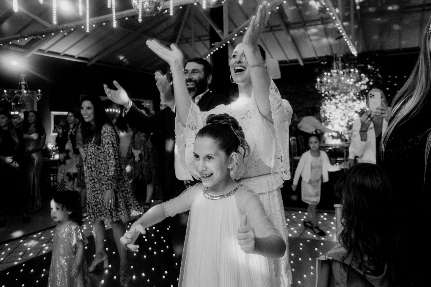 Dynamic black and white shot of joyful dancing at a wedding celebration with sparkles.