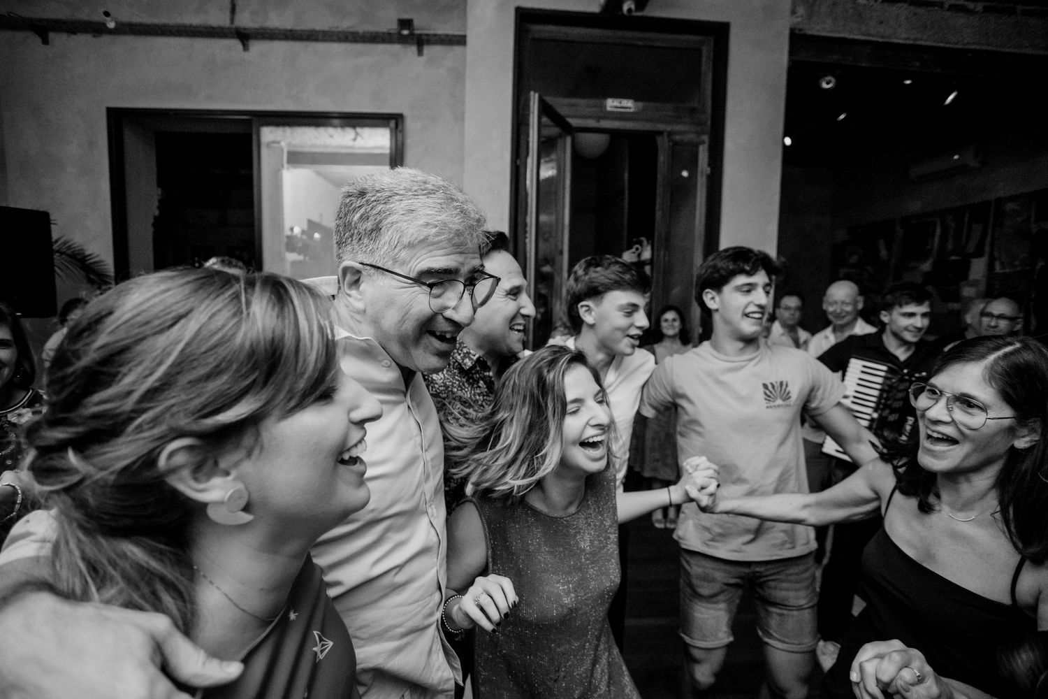 A crowd of excited party-goers laughing and cheering together at an indoor event.