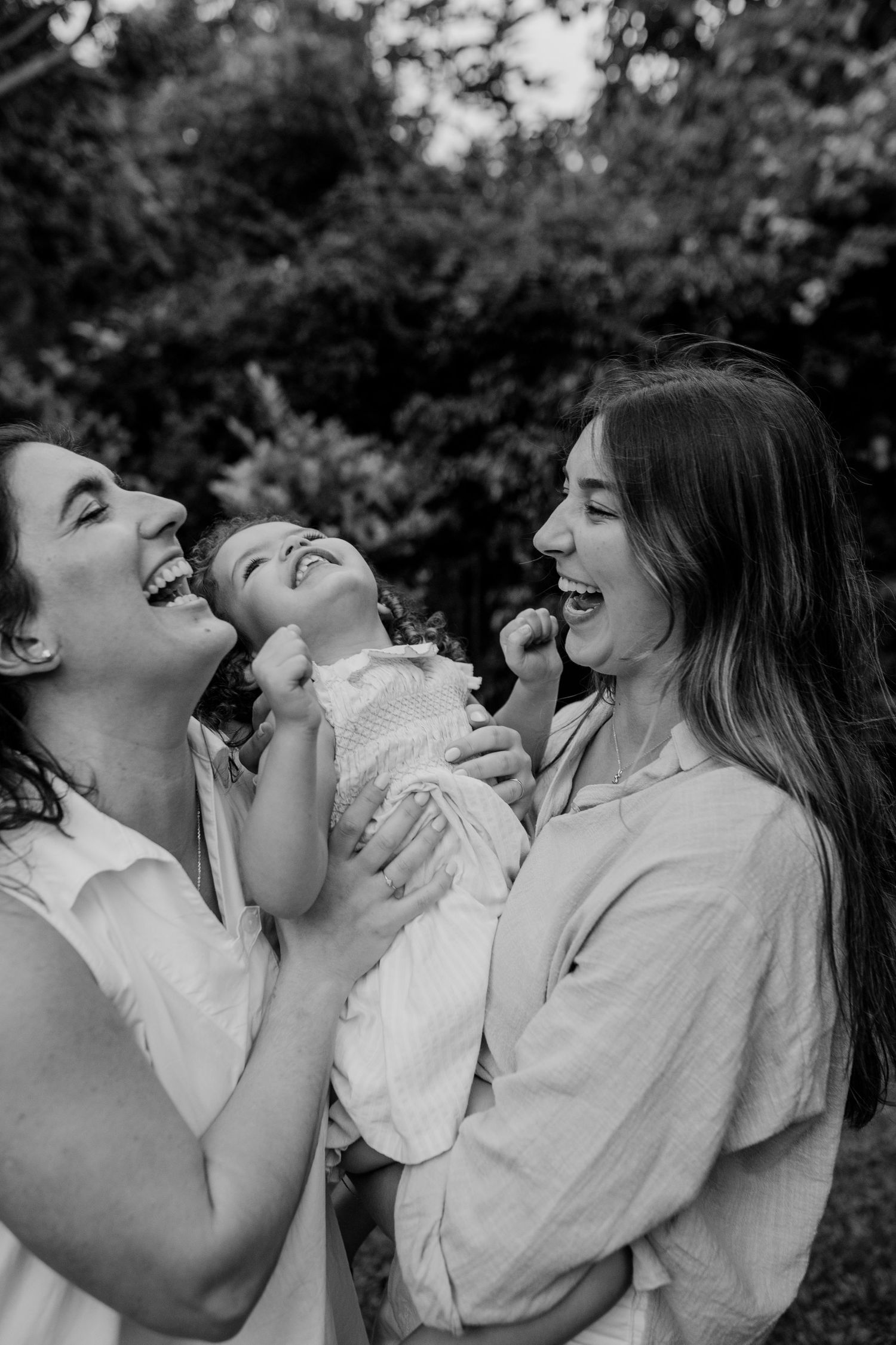 A black and white candid photo of a joyful moment shared between people laughing and embracing outdoors.