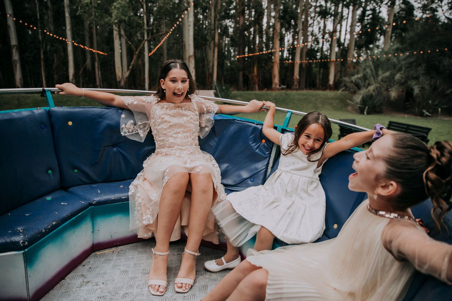 Children playing and posing on blue outdoor furniture amid eucalyptus trees.