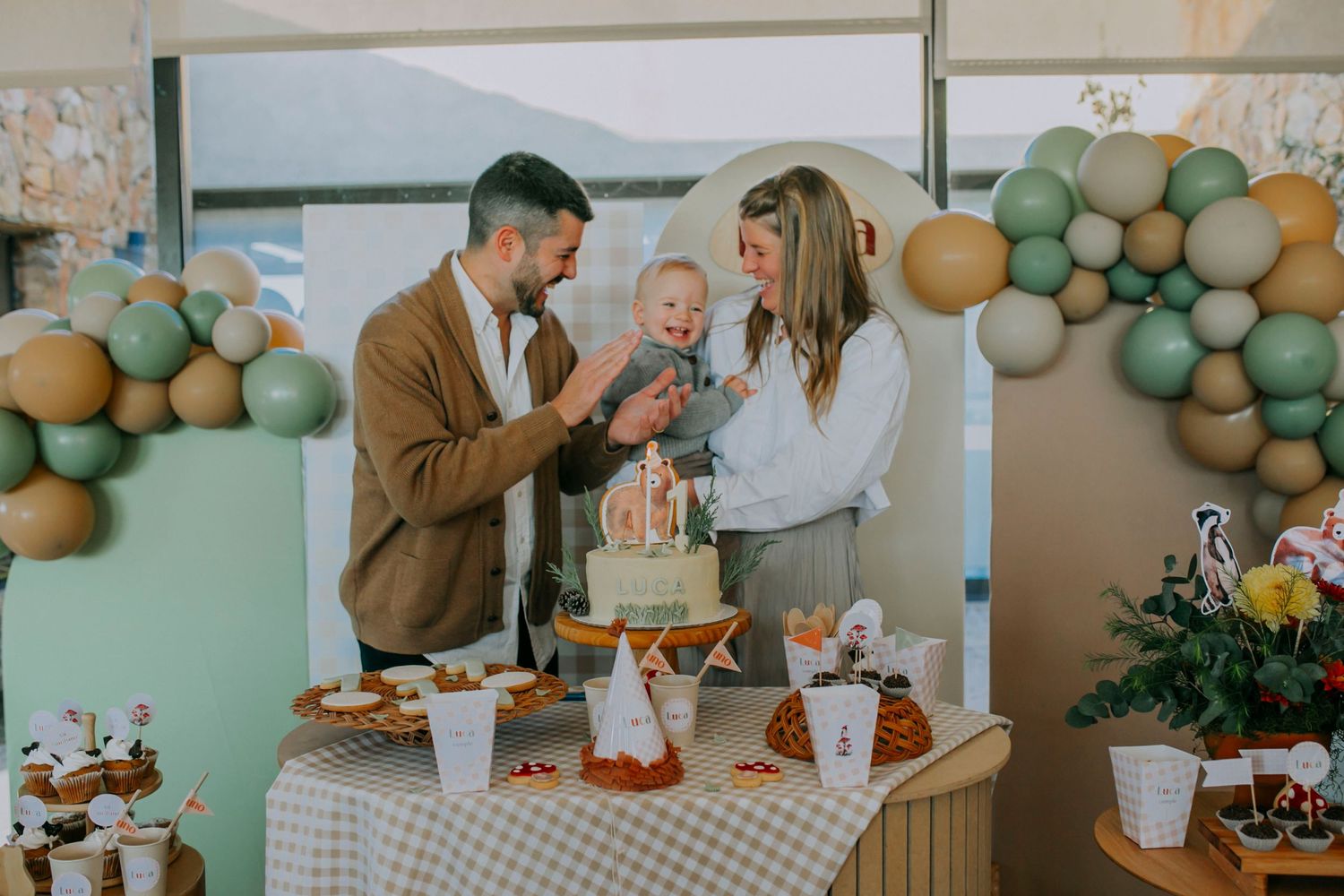 Party setup with balloon arch and dessert table featuring pastel green and gold decor.