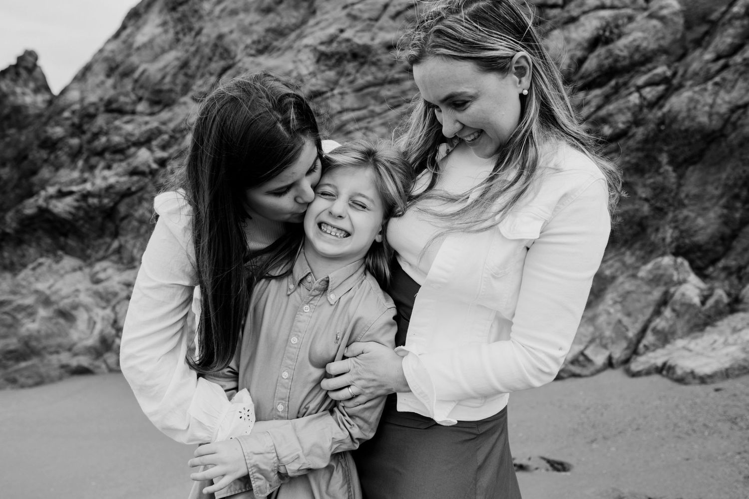 A candid black and white photo of a tender family moment at the beach.