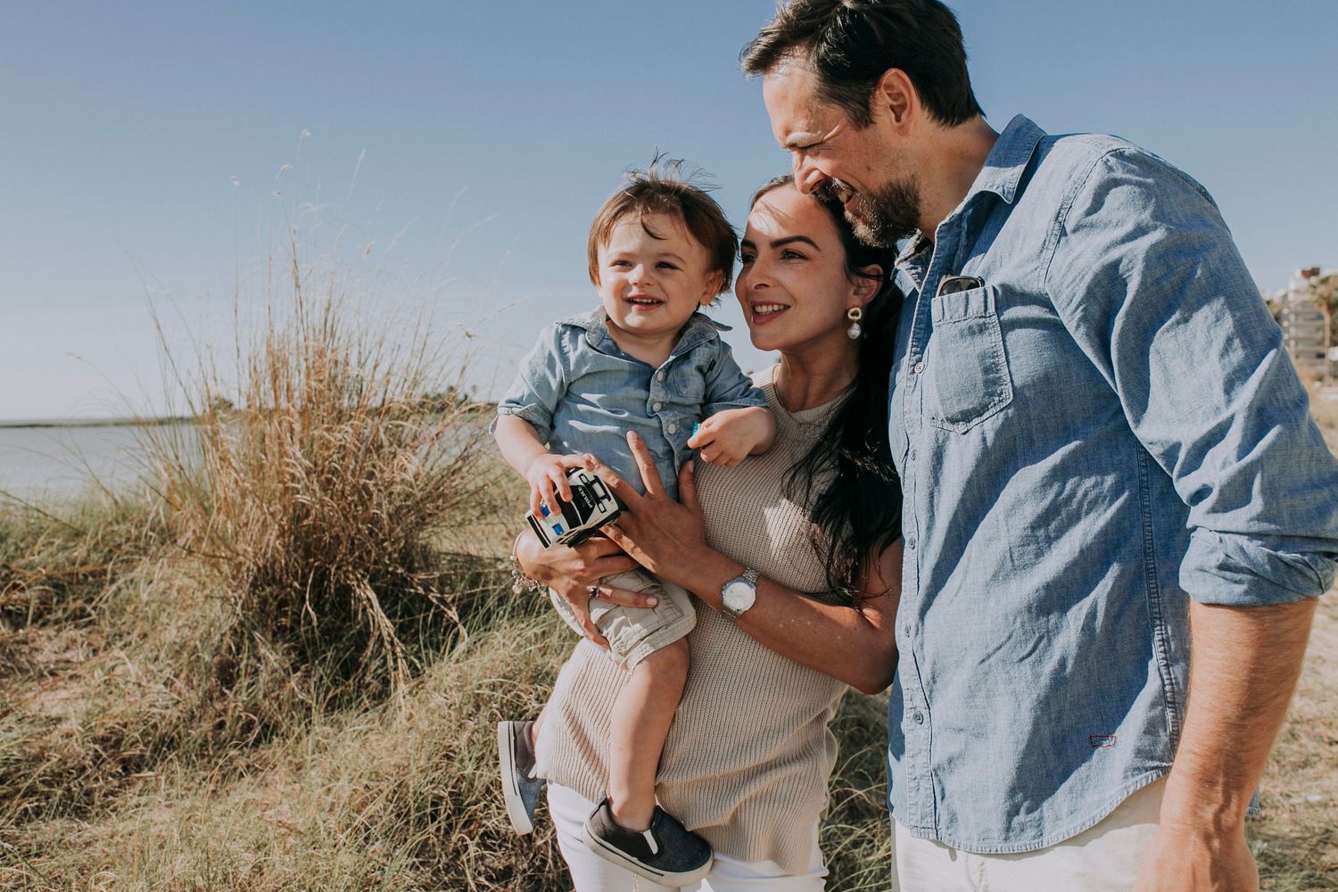 A tender family moment captured in nature with coastal waters in the background.