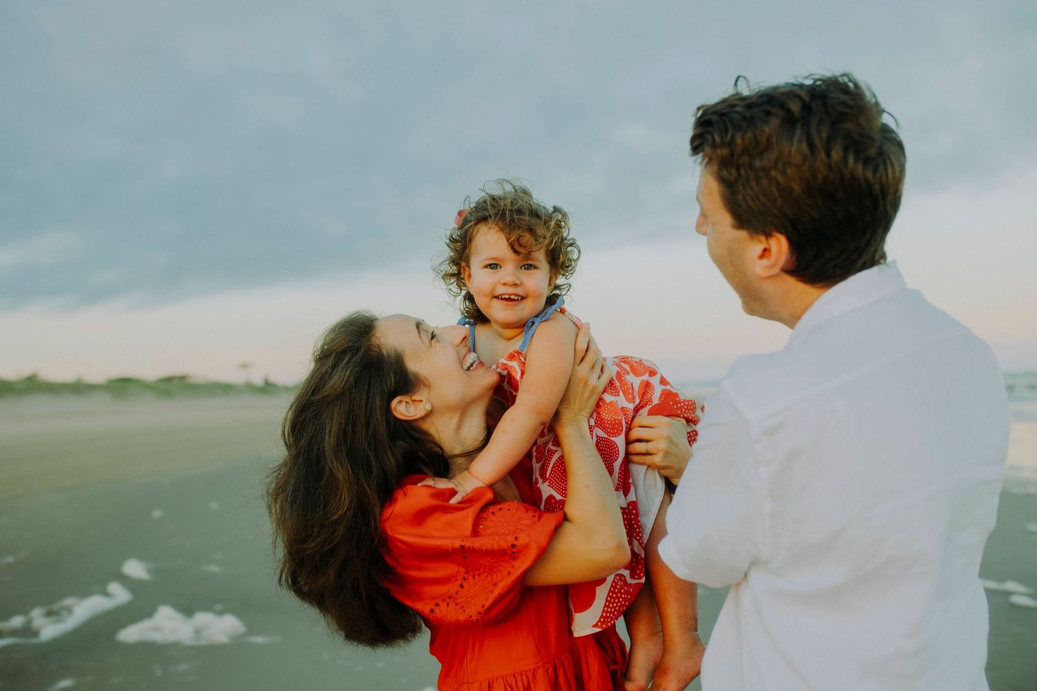 A sweet candid moment of playfulness and laughter at the beach during sunset.